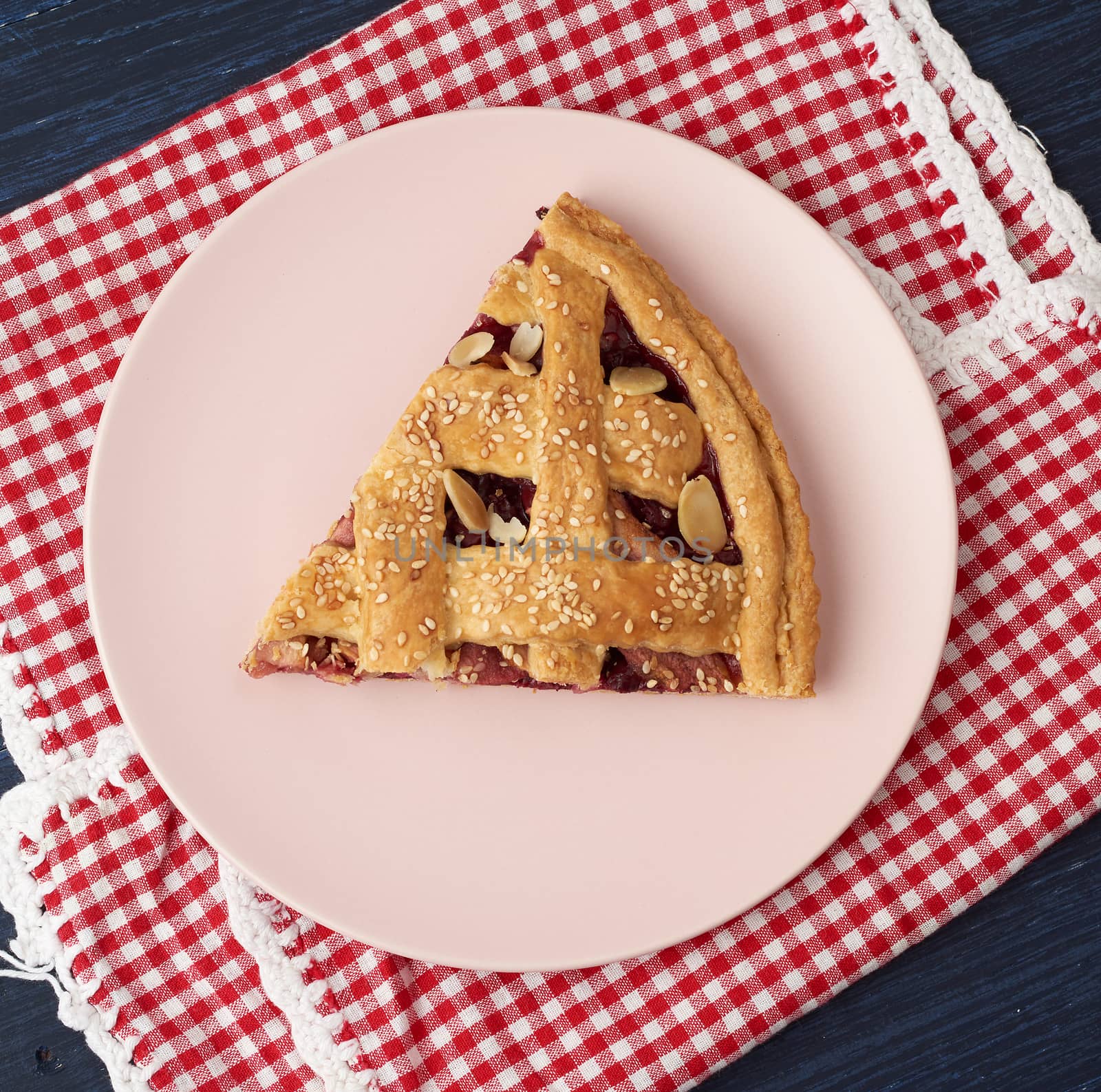triangular slice of baked cherry pie on a pink round plate by ndanko
