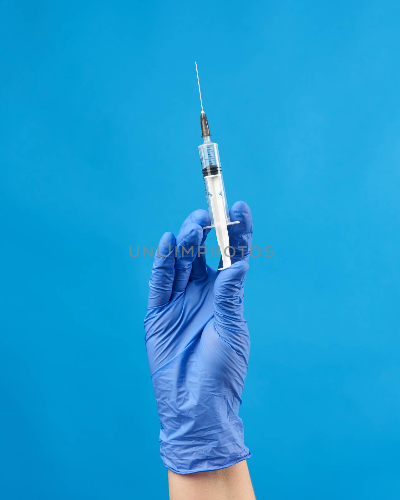 female hand in a blue sterile rubber glove holds a white syringe by ndanko