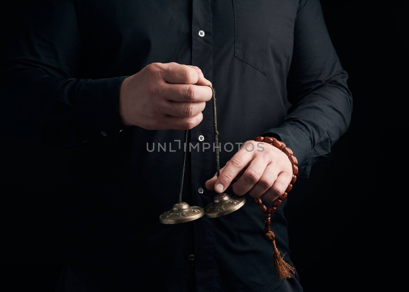 adult man in black clothes holds in his hands a pair of bronze K by ndanko