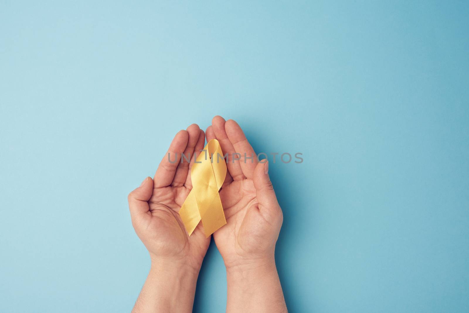 two female hands hold in their palms a yellow ribbon in the form by ndanko