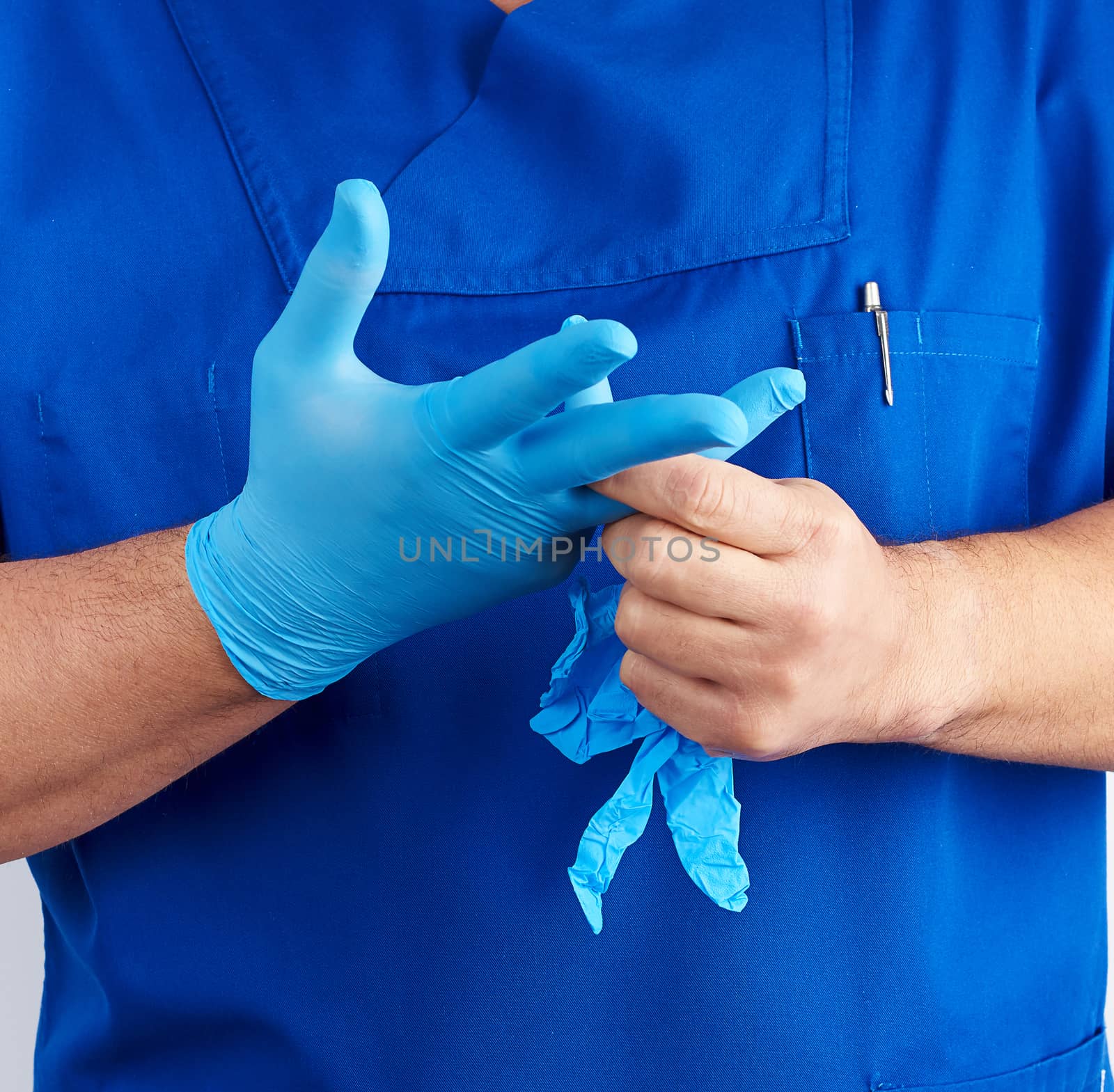 adult male doctor in blue uniform puts on his hands blue sterile by ndanko
