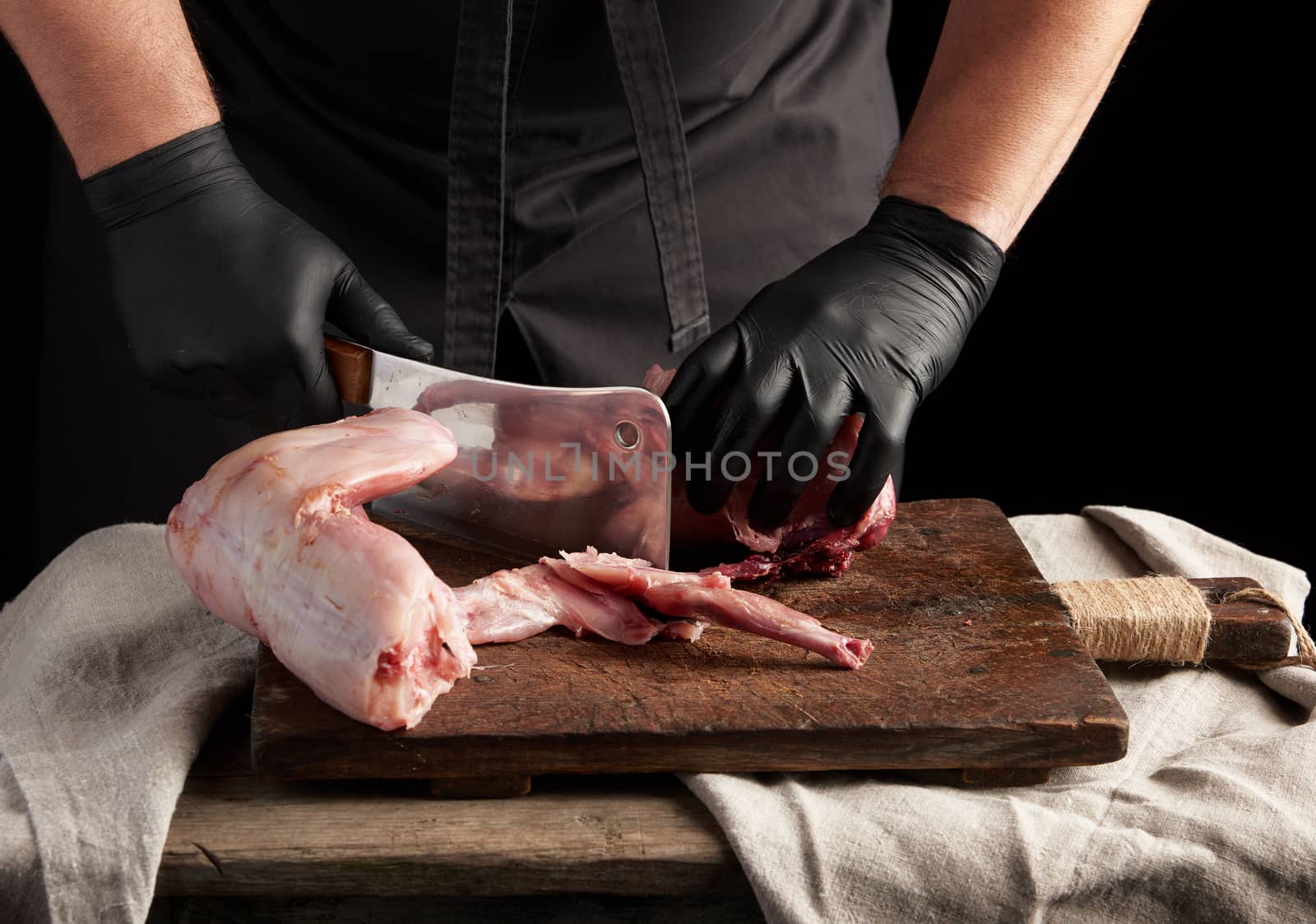Chef in black latex gloves holds a big knife and cuts into piece by ndanko