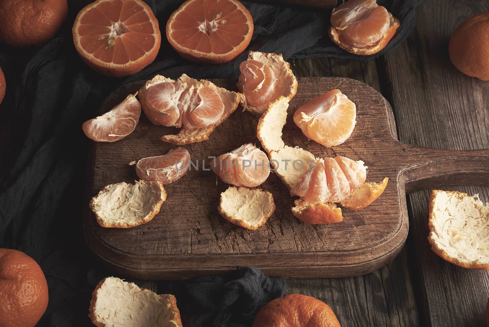 ripe round tangerines and cut in half on an old vintage cutting  by ndanko
