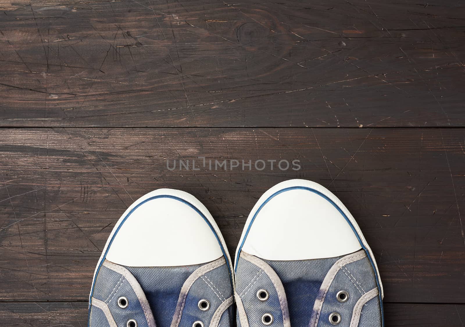 blue men's old  sneakers on a brown wooden surface by ndanko