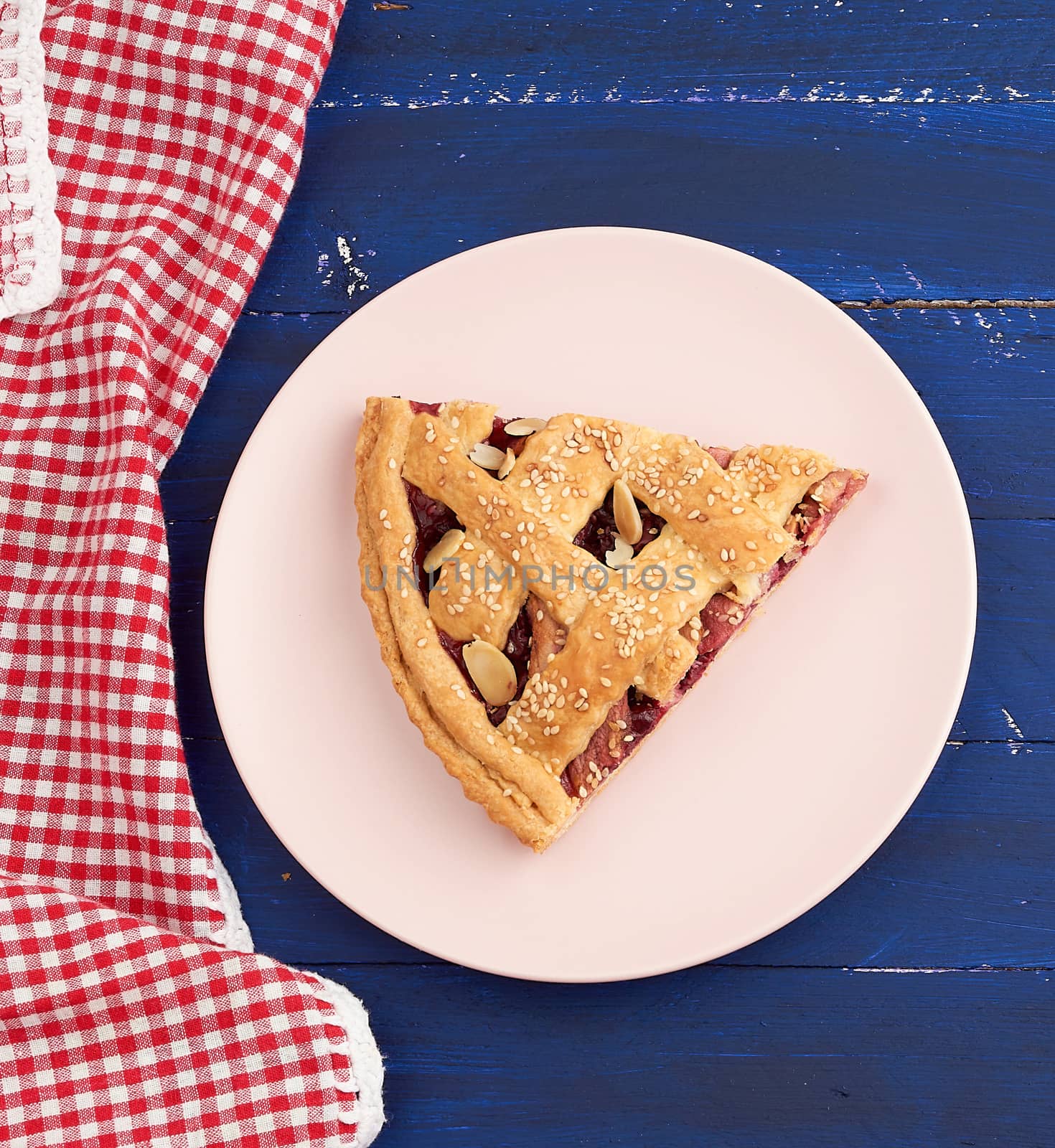 triangular slice of baked cherry pie on a pink round plate, top view, copy space