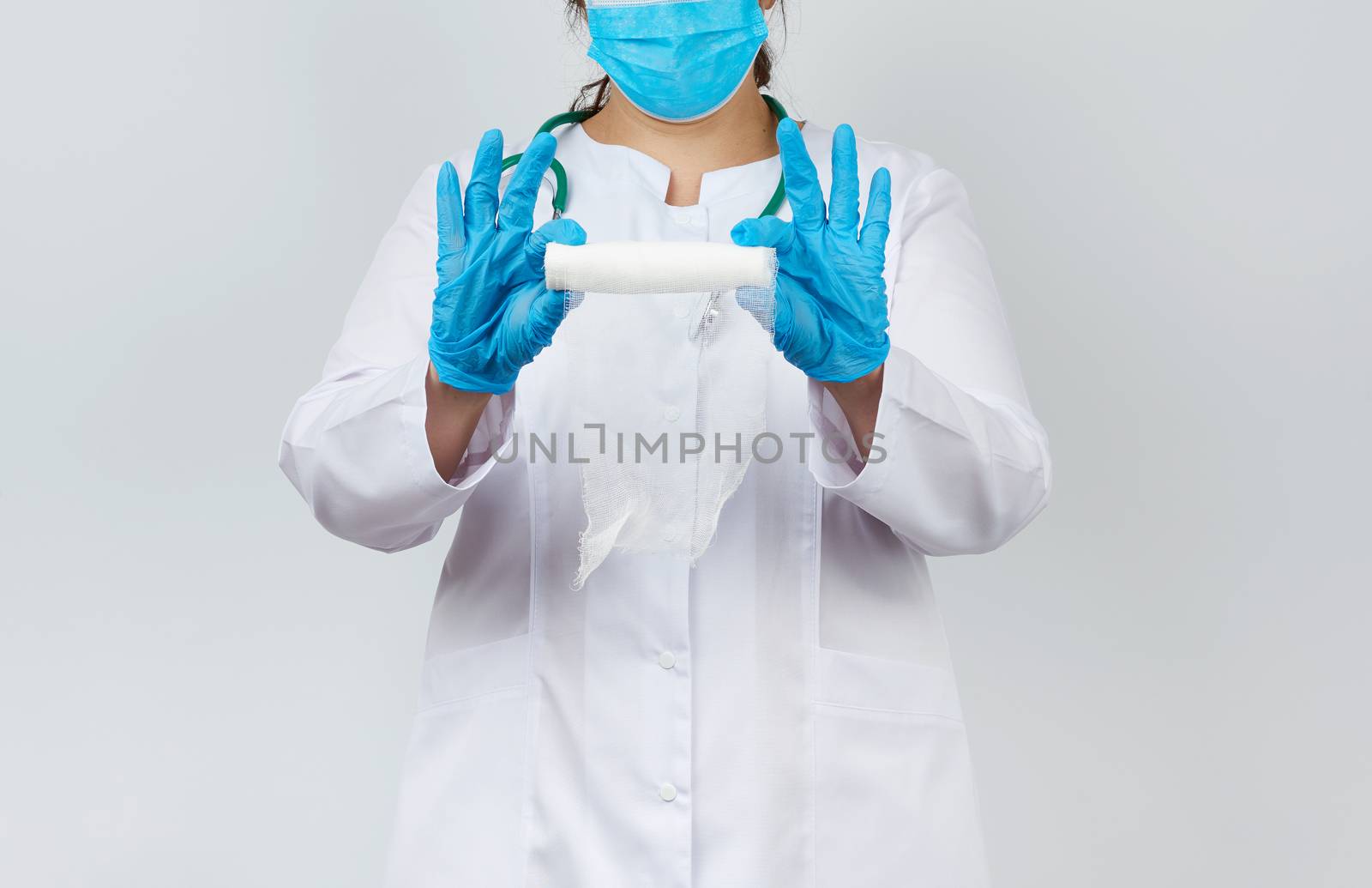 medic woman in white coat and mask holds a twisted gauze bandage for dressing wounds, white background