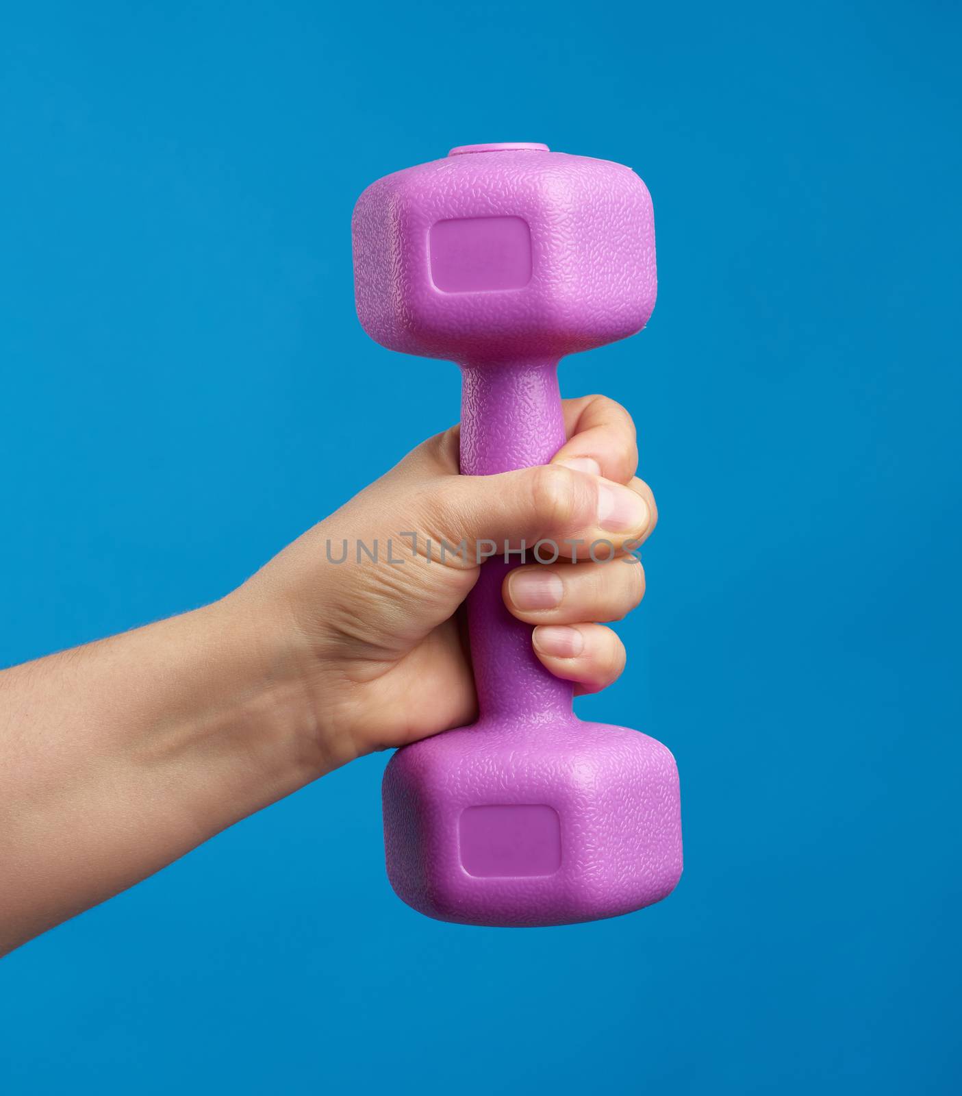 female hand holds a plastic pink dumbbell on a blue background by ndanko