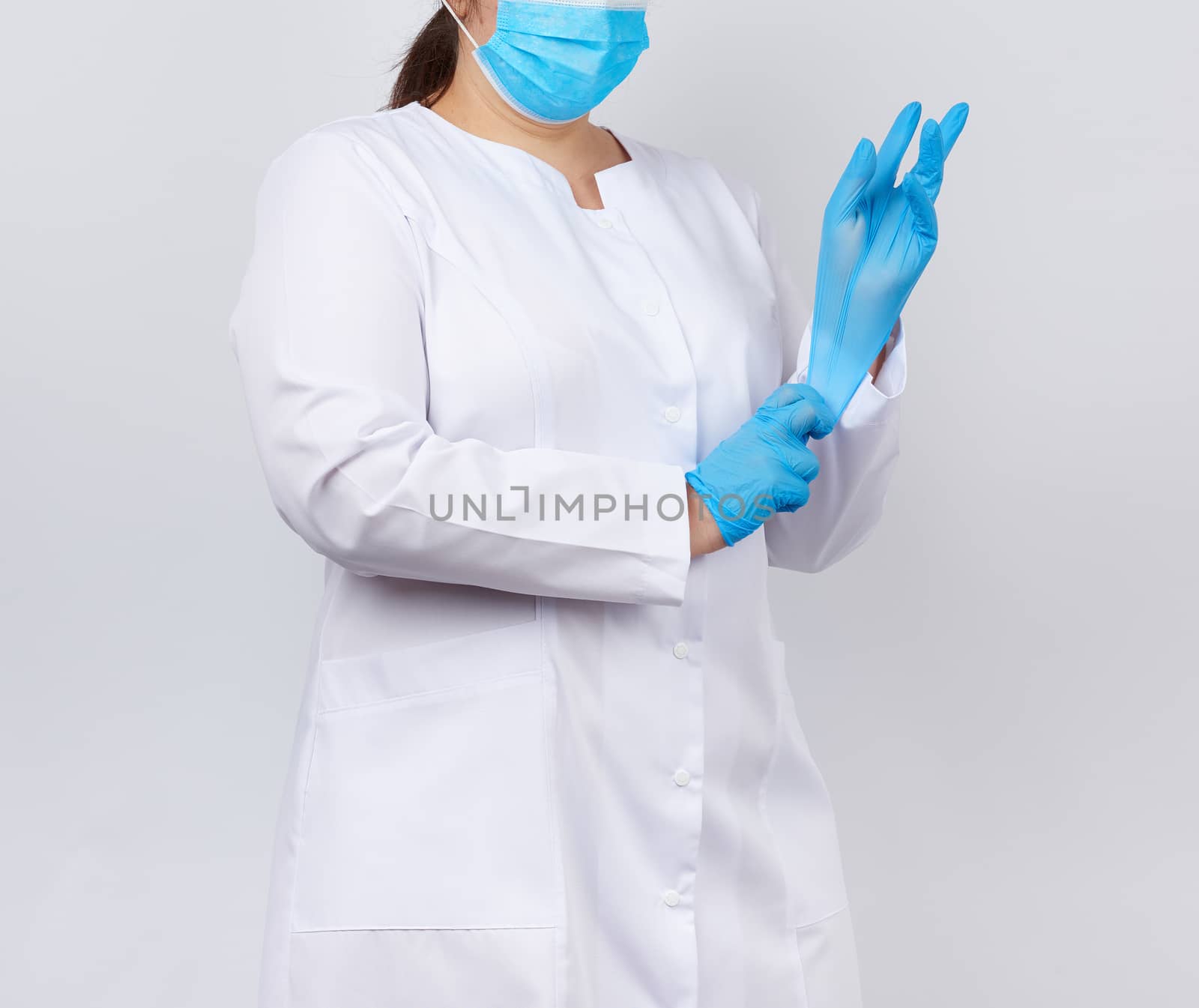 medical doctor in a white coat and mask puts on medical hands la by ndanko