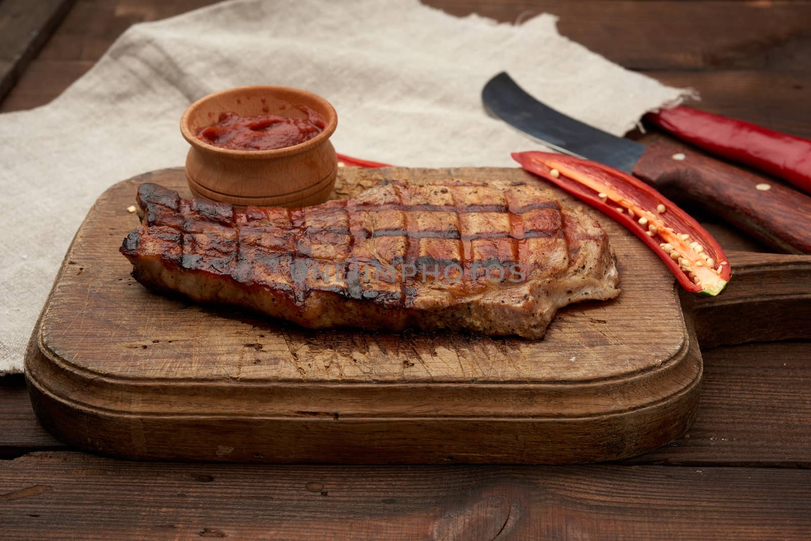 pork fried steak on the rib lies on a vintage brown wooden board by ndanko