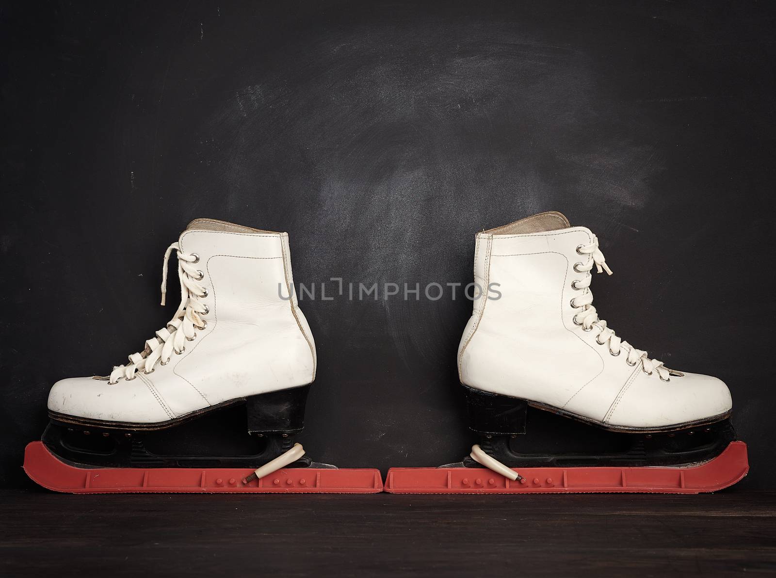 white leather skates for figure skating stand on a brown wooden background, sports equipment, copy space