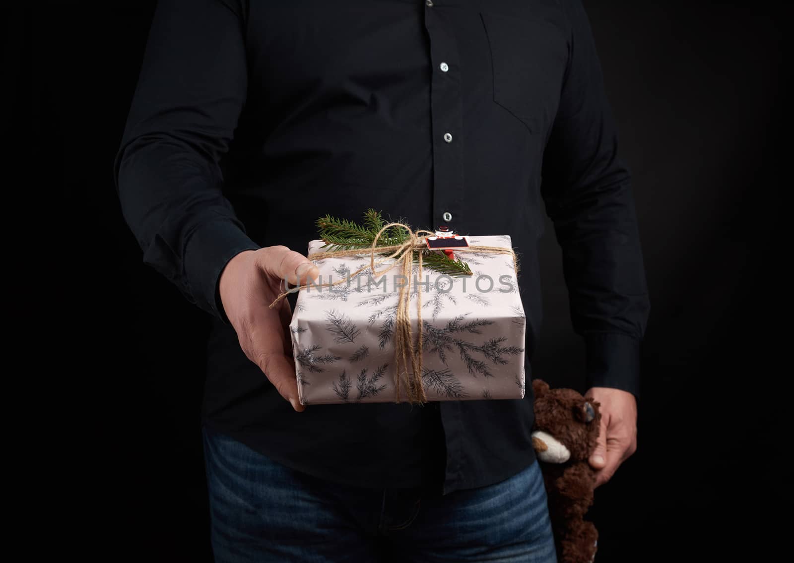 adult man in a black shirt holds a square box and brown teddy be by ndanko