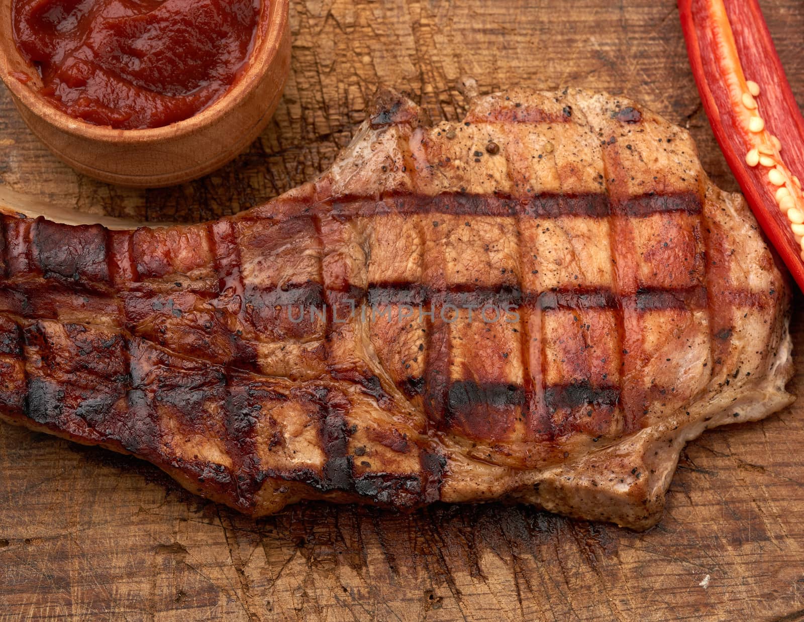pork fried steak on the rib lies on a vintage brown wooden board by ndanko