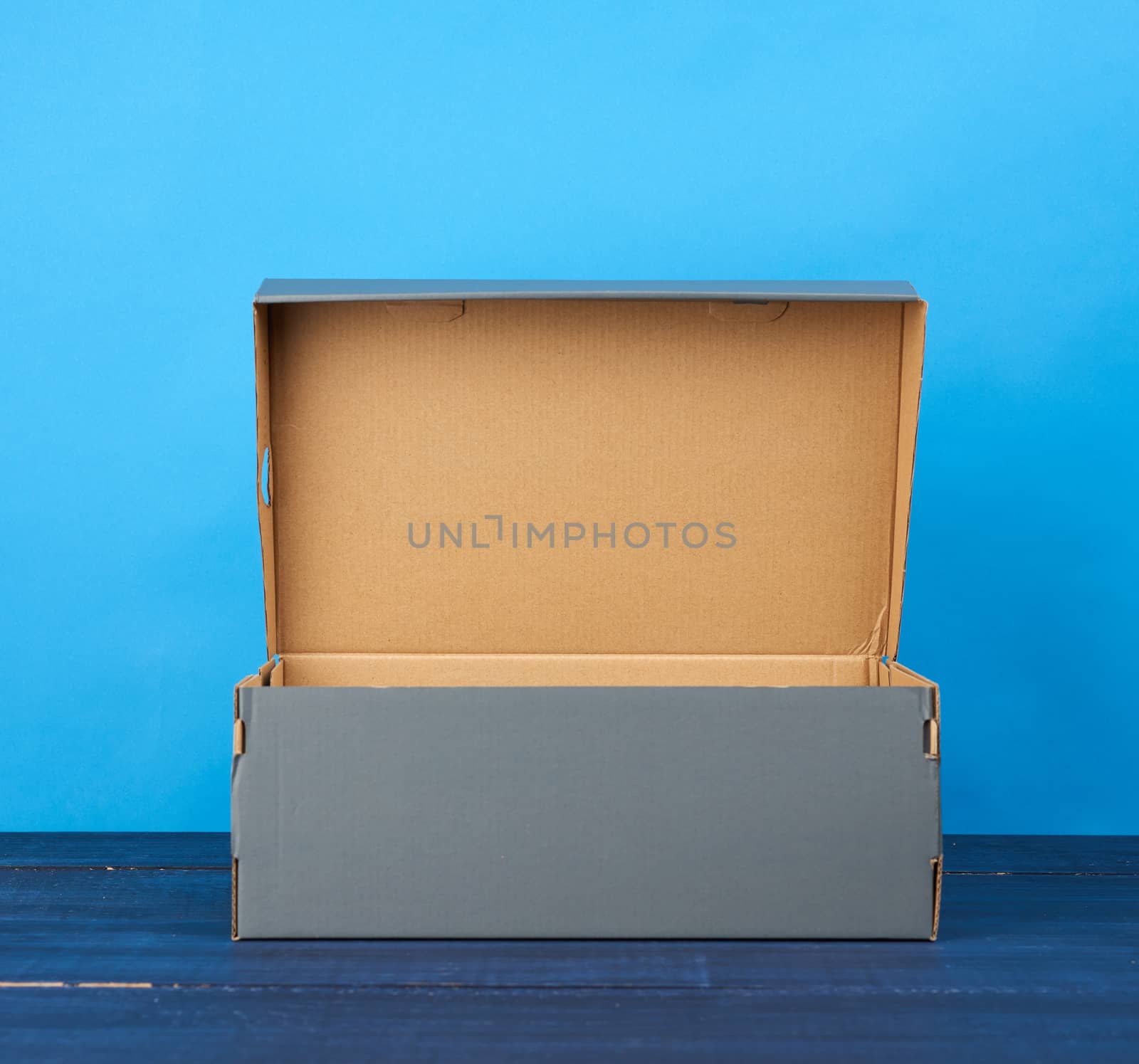 empty open cardboard box for shoes on a blue background by ndanko
