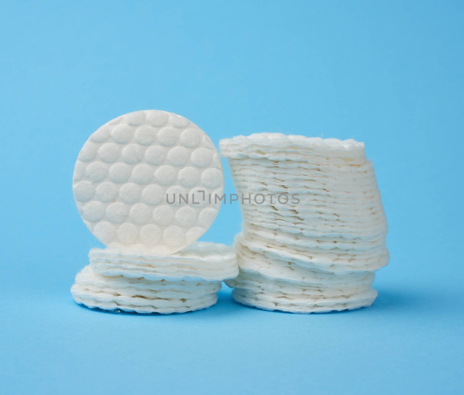 white round cotton discs for removing makeup on a blue background, close up