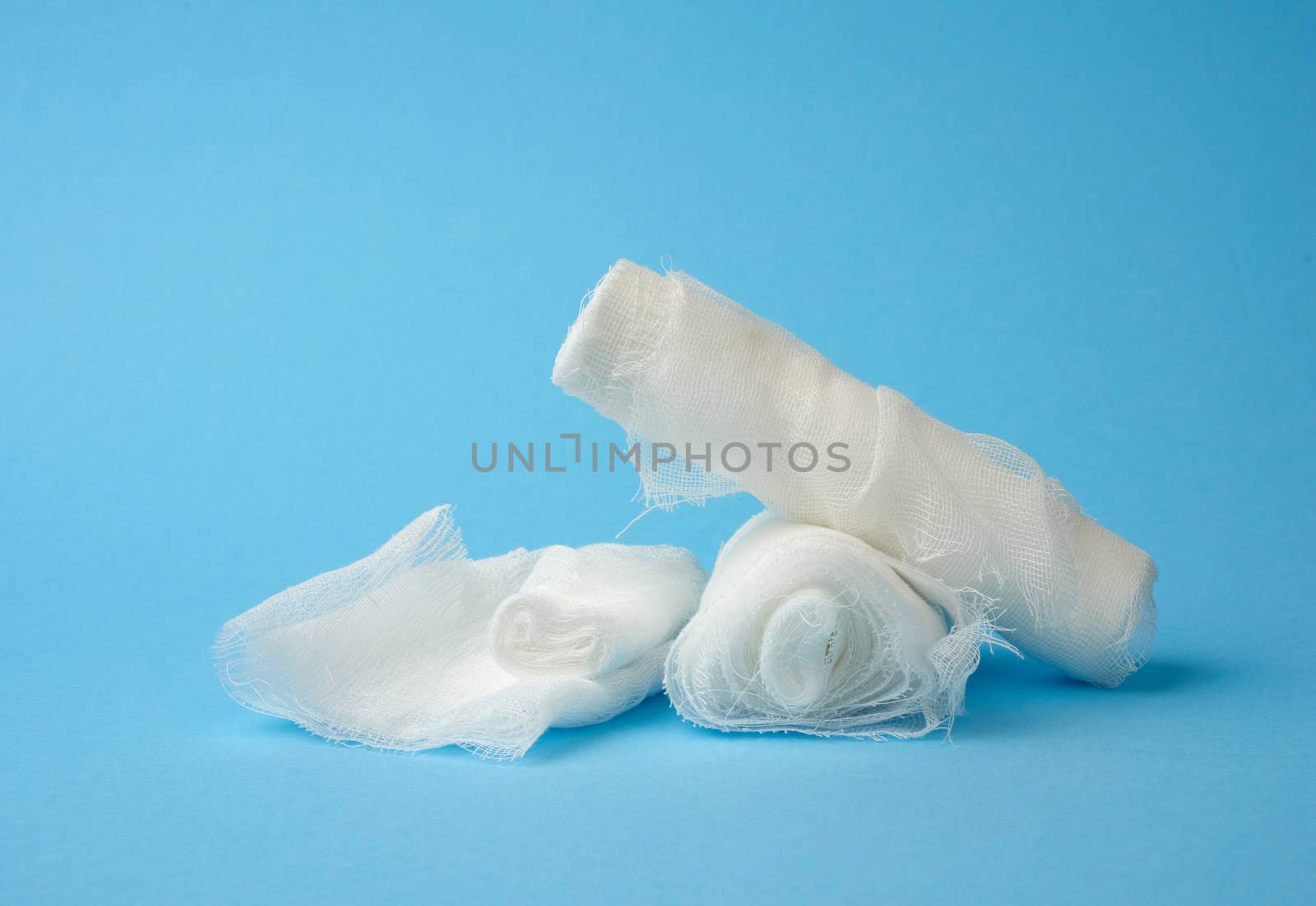 stack of white medical gauze cotton bandages on a blue background, close up