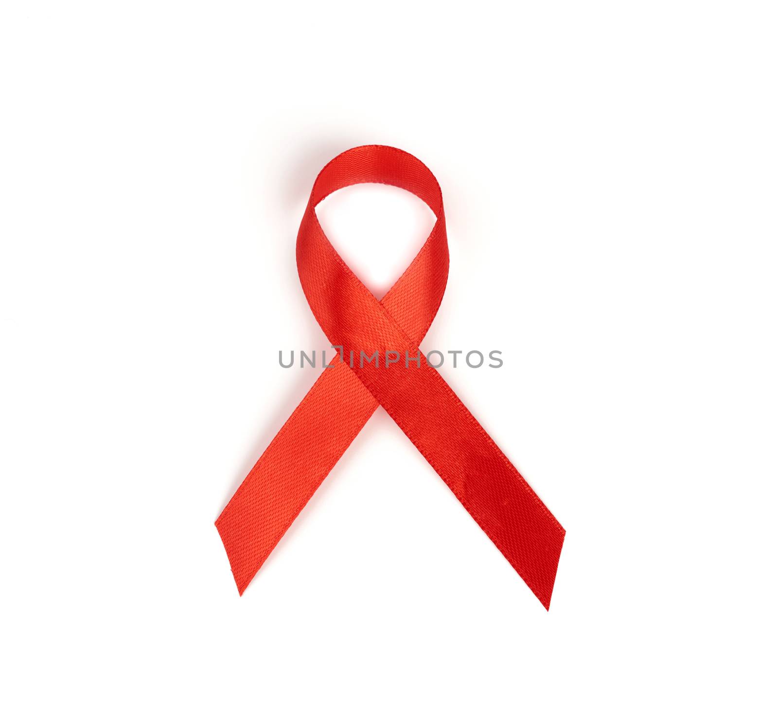 red silk ribbon twisted into a loop.  Symbol of AIDS or HIV awareness isolated on white background

