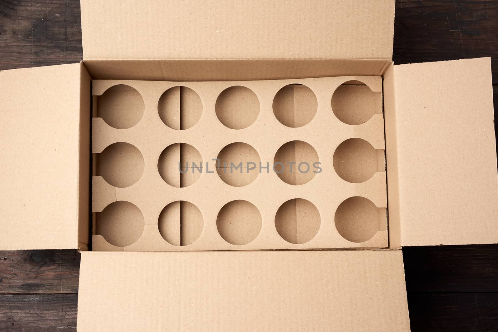 open empty brown cardboard box with round cells for cans, top view
