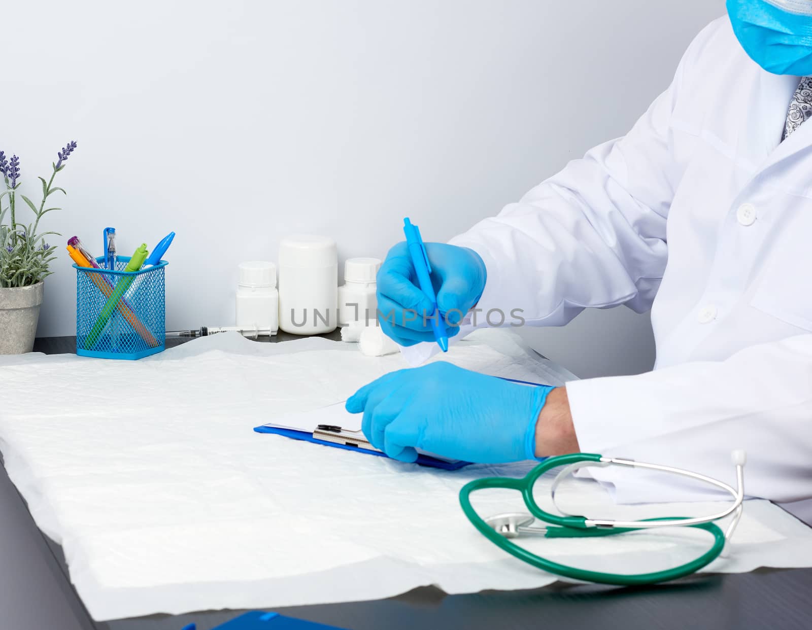 doctor in a white medical coat sits at a table and writes with a pen on a white sheet of paper,  concept of patient admissions