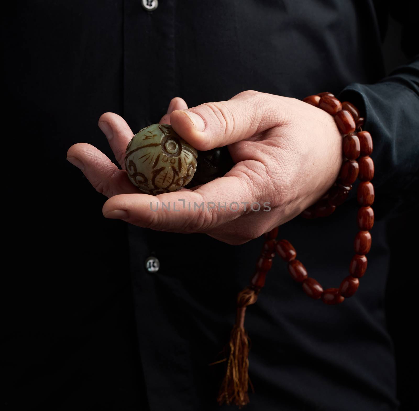 adult man in black clothes holds in his hands a stone magic ball, object for religious rituals, meditations and alternative medicine