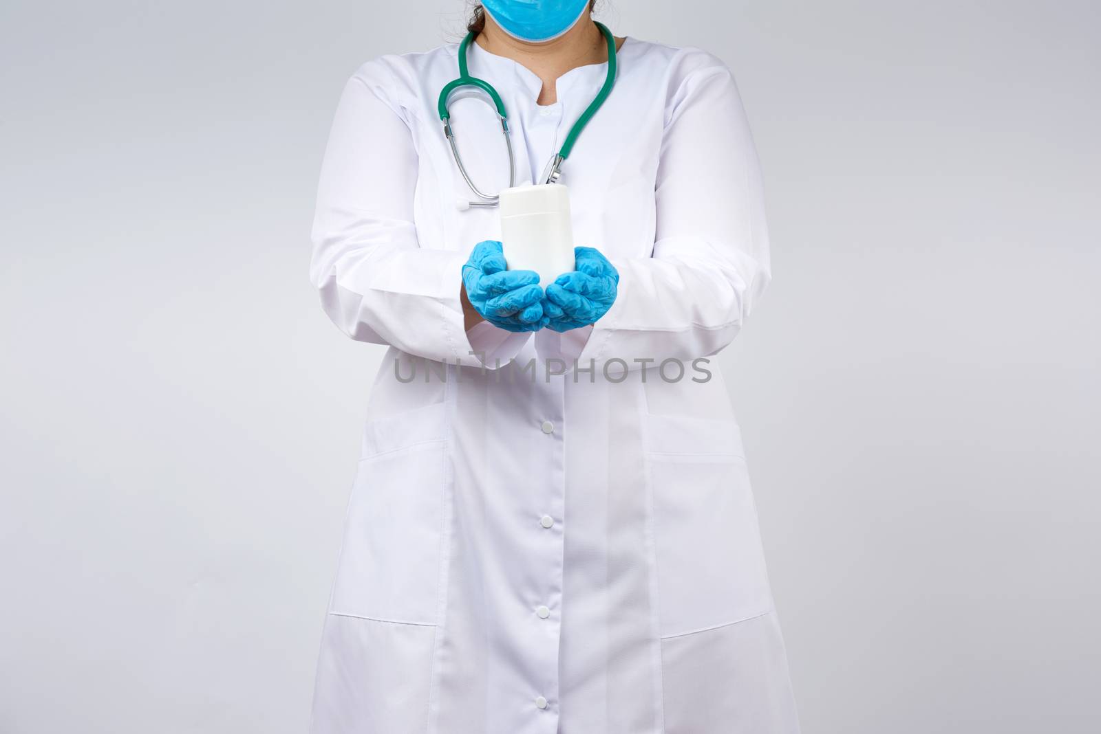 female doctor in a white coat and mask holds a white plastic jar for medicines and pills, wearing blue latex gloves,  white background