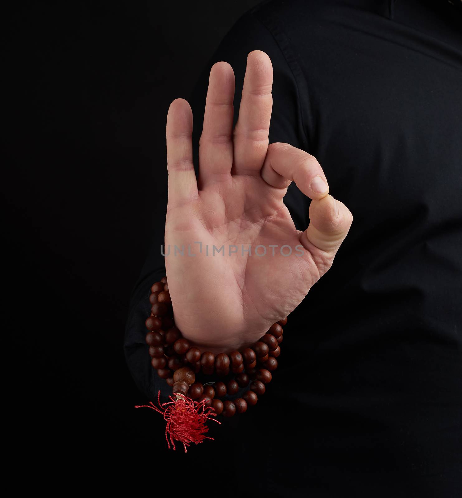 hand of an adult male shows om mudra on a dark background by ndanko