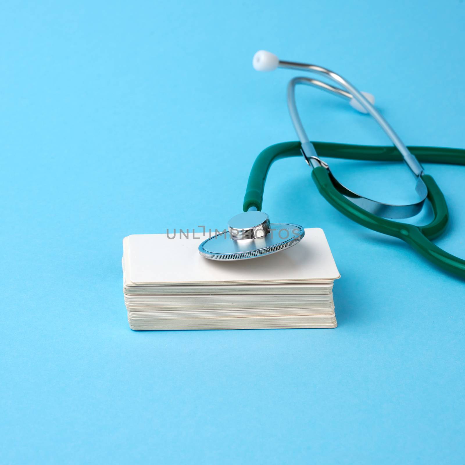 medical stethoscope and empty paper business cards on a blue background, selective focus