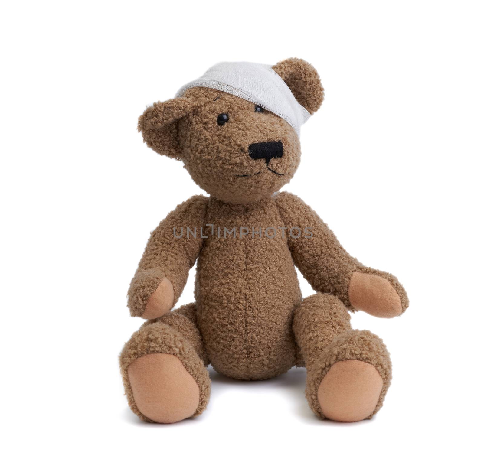 brown teddy bear with a bandaged head in a white medical bandage on a white background, concept of child trauma, headache