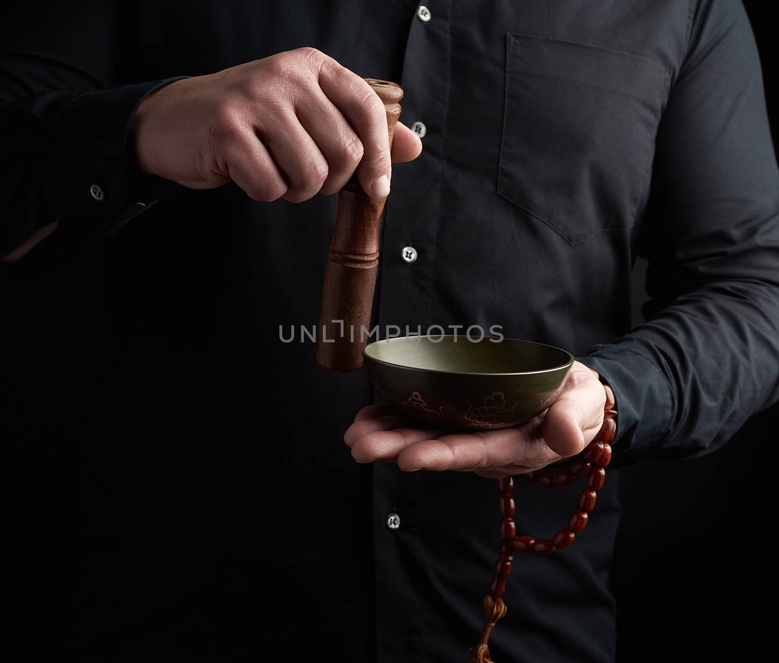 adult man in a black shirt rotates a wooden stick around a coppe by ndanko