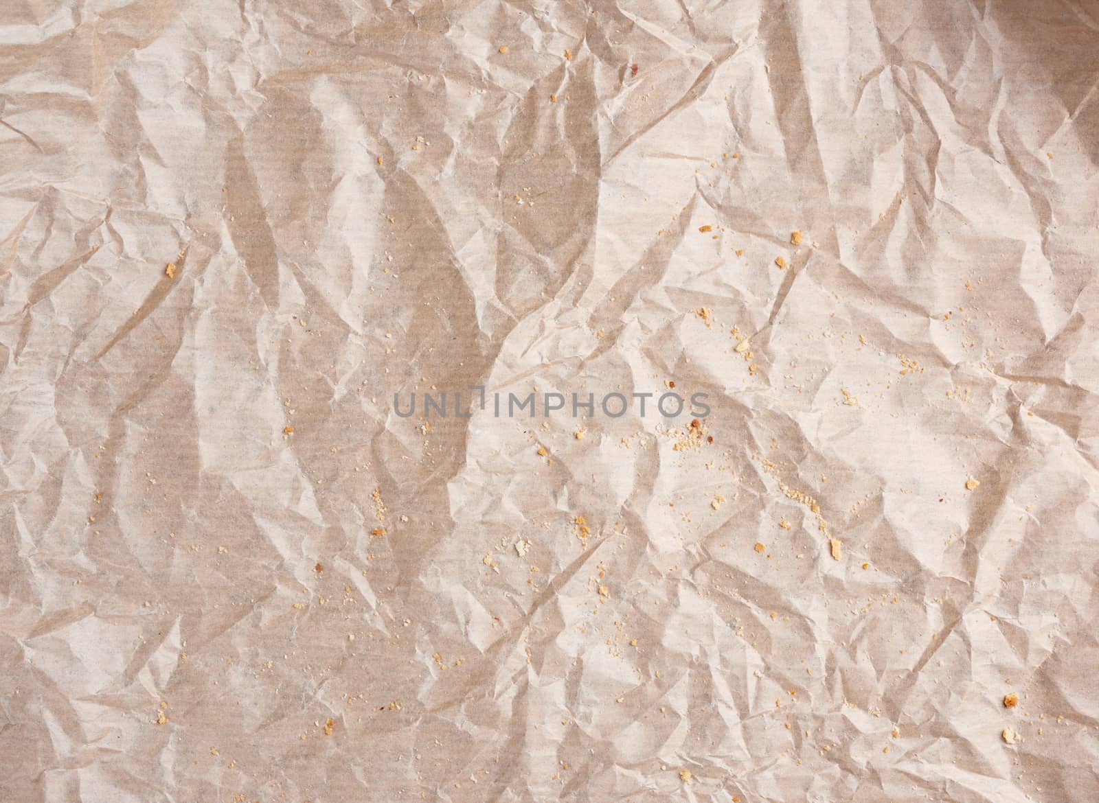 crumpled brown parchment paper with bread crumbs, full frame