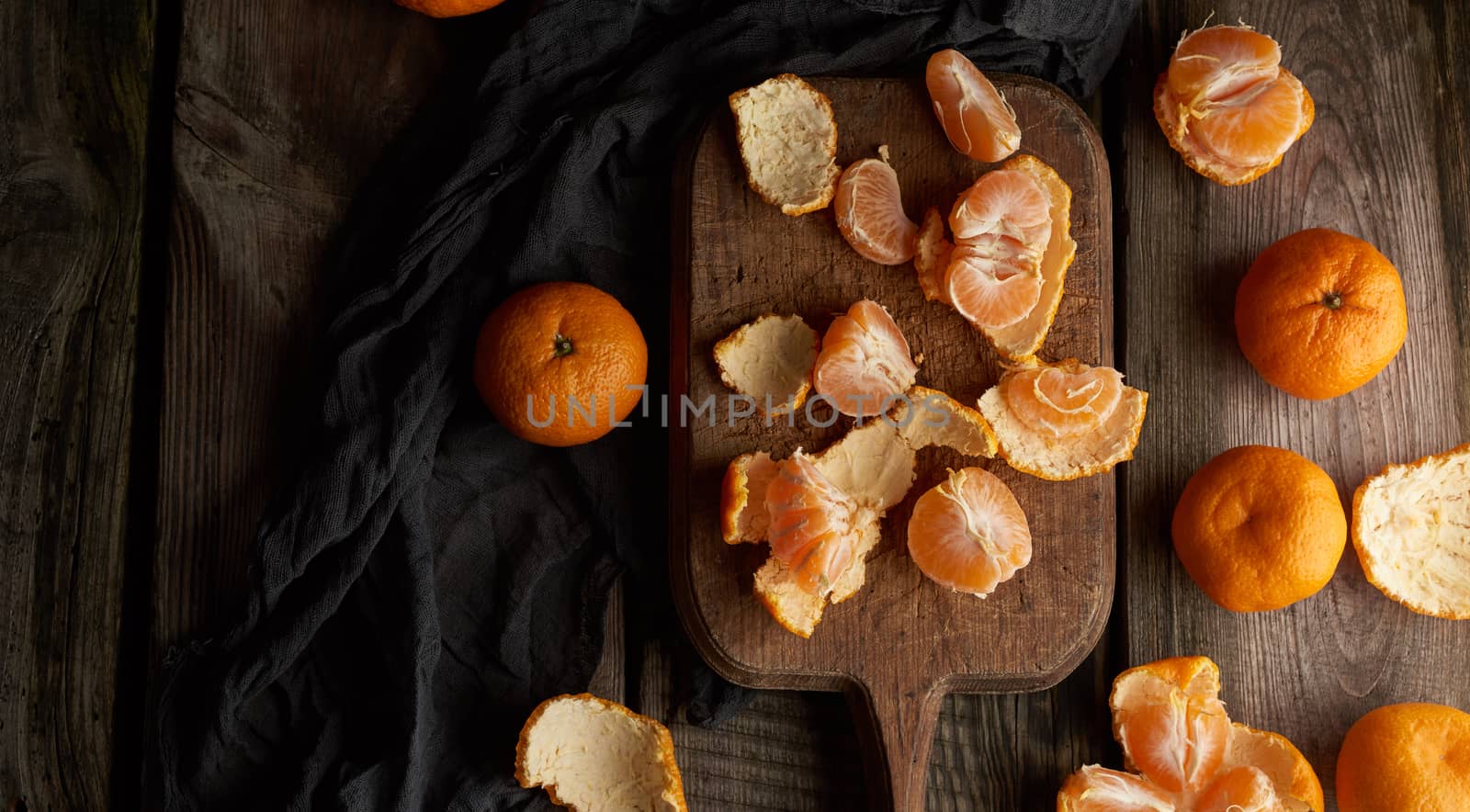 ripe round tangerines and cut in half on an old vintage cutting board. Healthy vegetarian food. Citrus fruit, top view