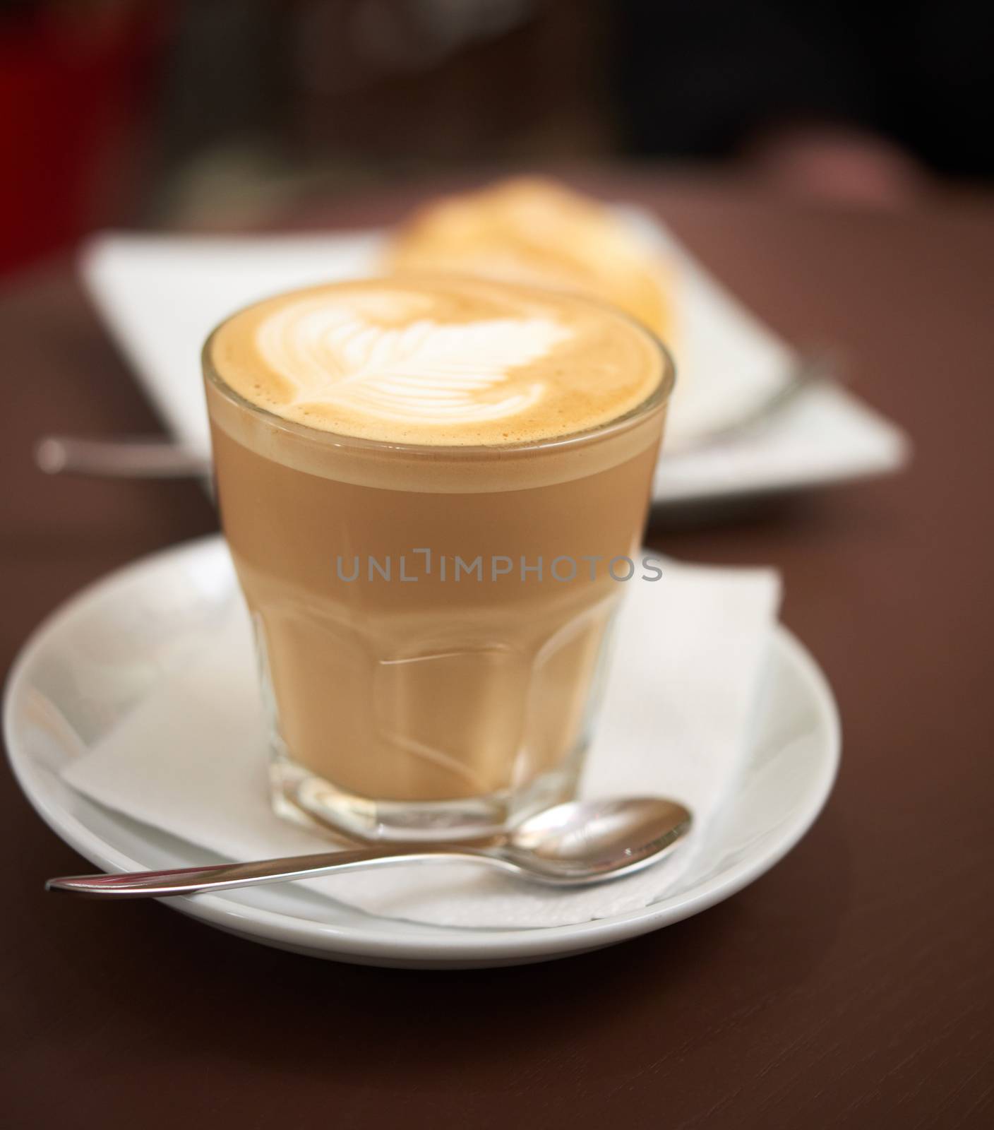 flat white coffee in a transparent glass with white foam, food on the table in a cafe