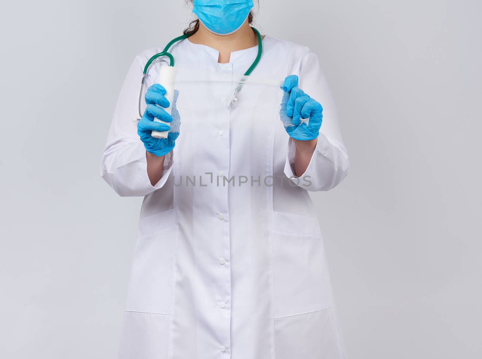 medic woman in white coat and mask holds a twisted gauze bandage for dressing wounds, white background