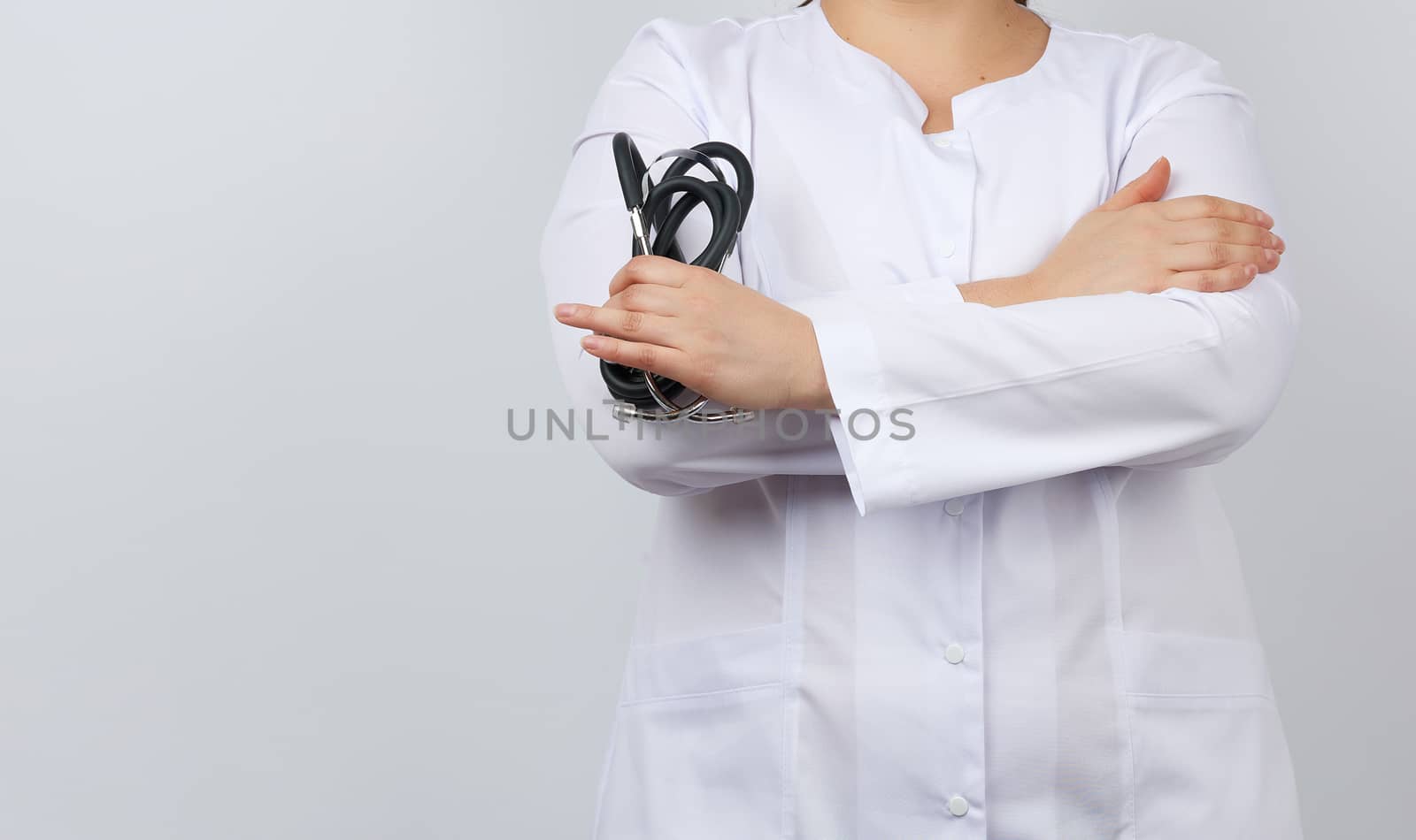 female medical doctor holding a black medical stethoscope in her hand on a white background, empty space for inscription