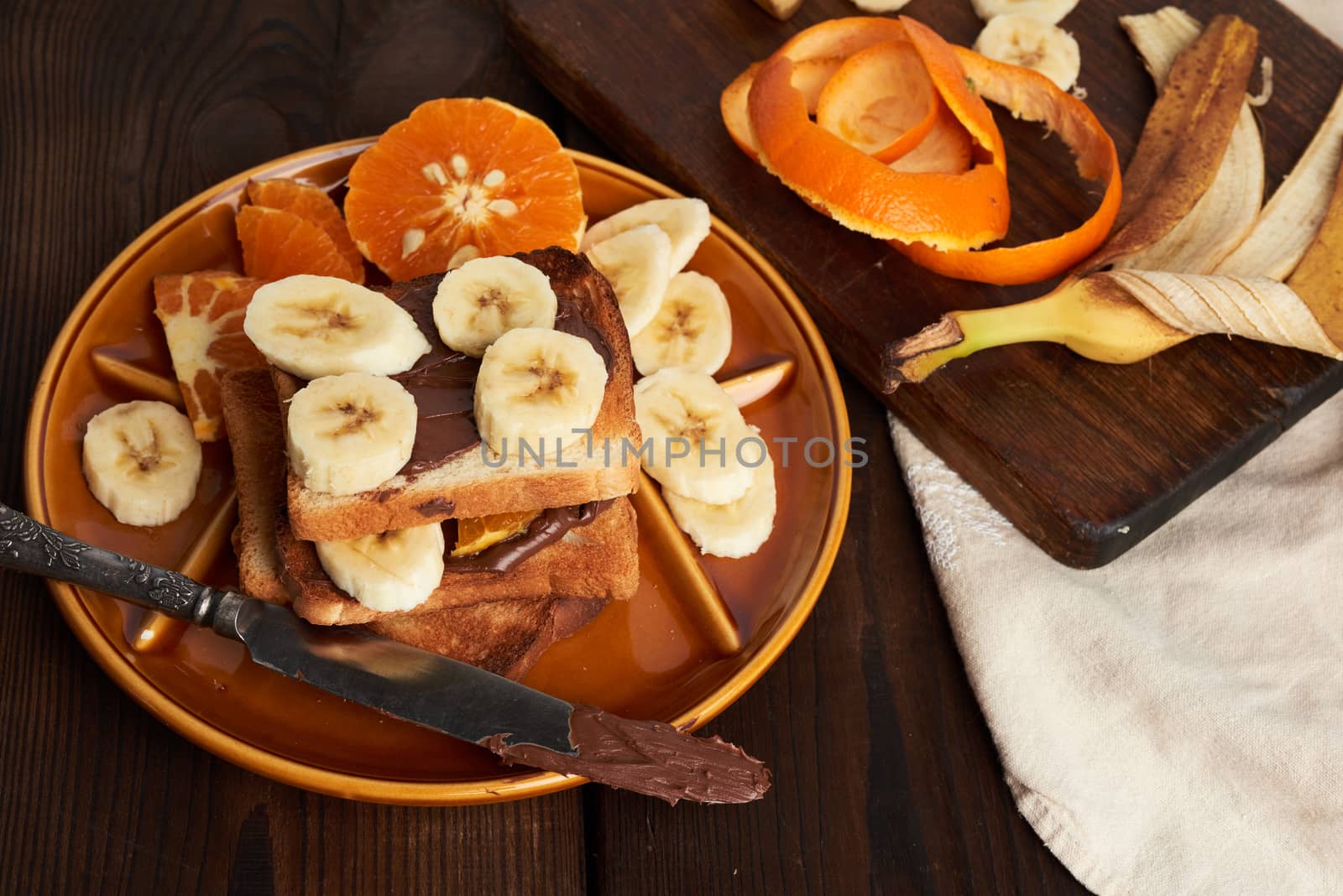 toasted sandwiches with chocolate paste and banana slices on a plate, morning breakfast, close up