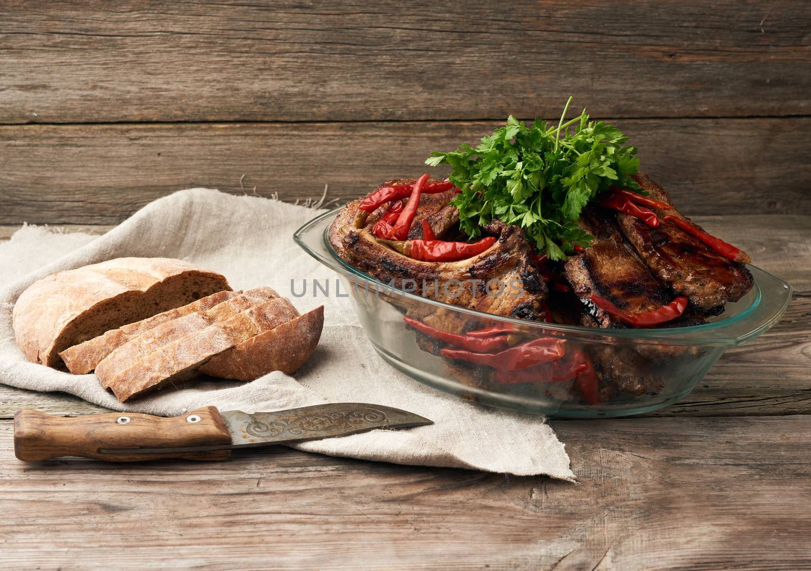grilled pork steaks on the bone lie in a transparent glass plate on a wooden table, barbecue