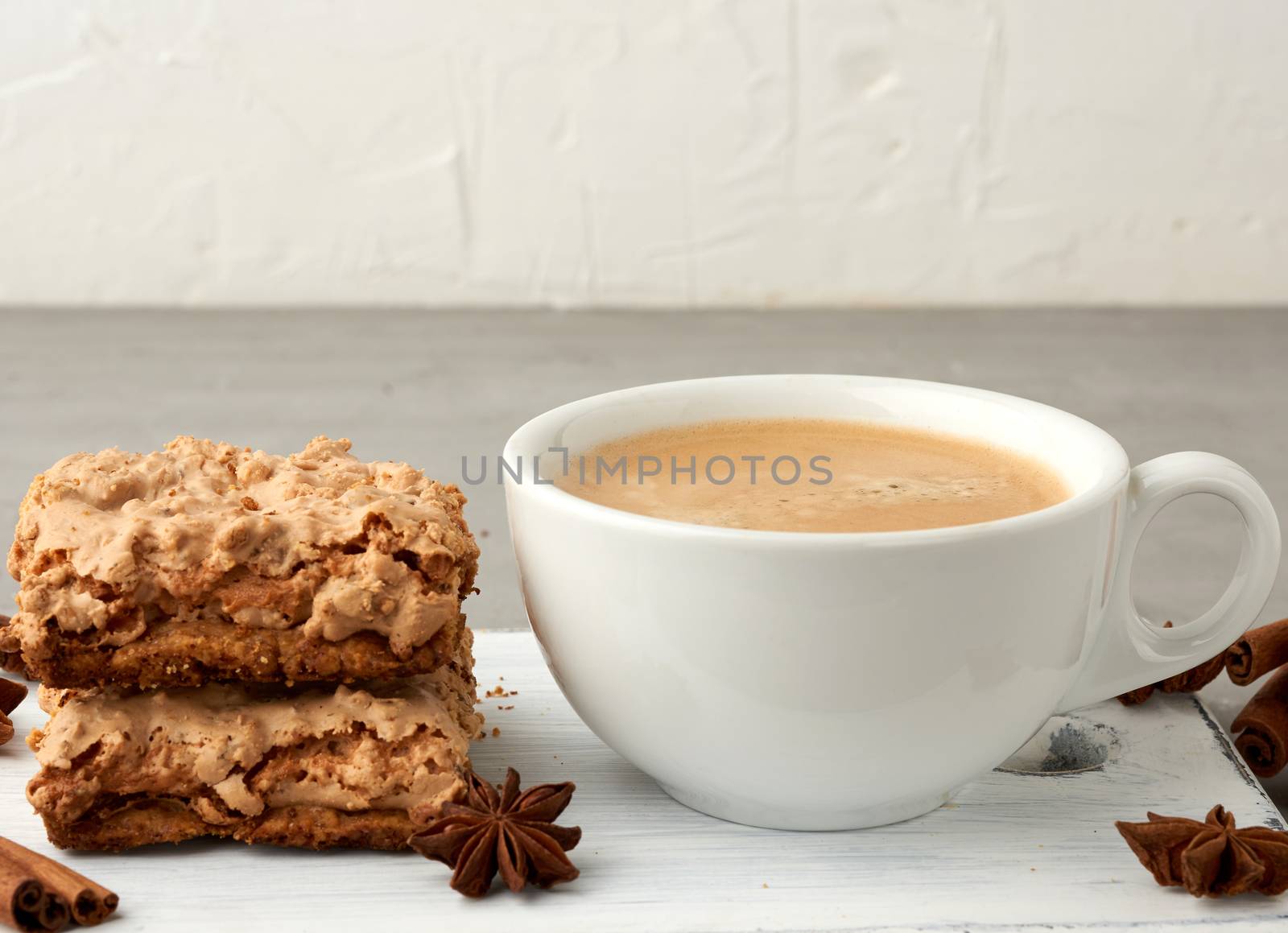 baked Krakow meringue cookies on a wooden board and a white ceramic cup with black coffee, delicious dessert of whipped egg whites and almond flour