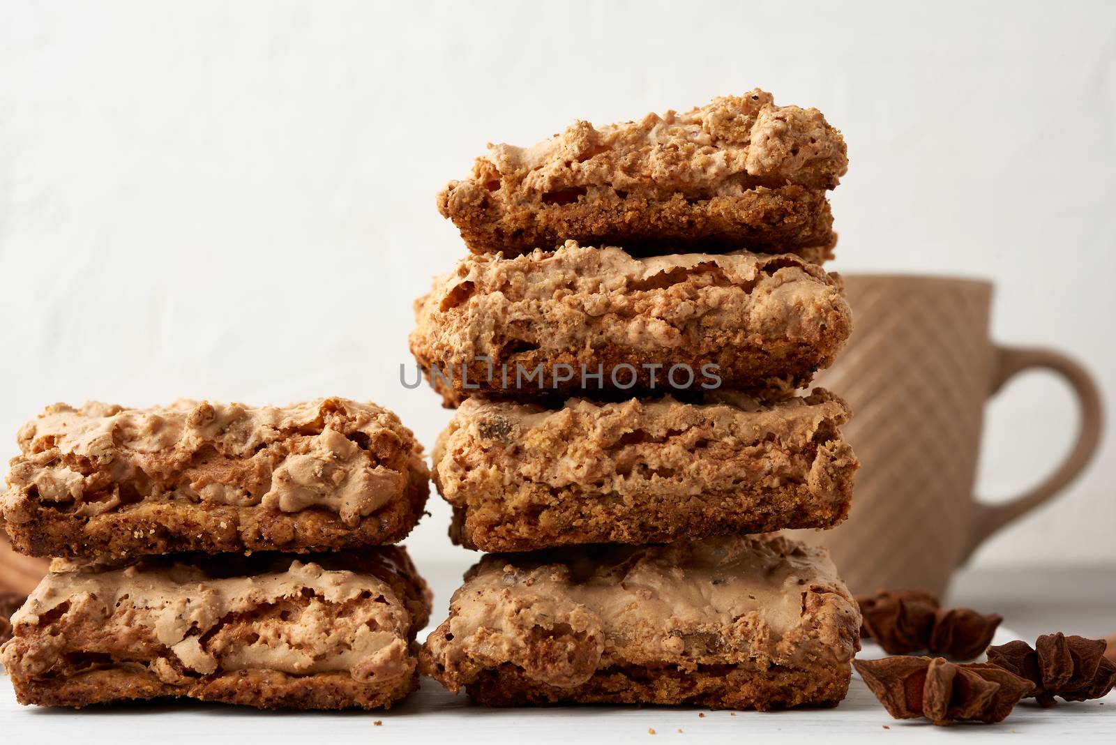 stack of baked Krakow meringue cookies on a wooden board and a white ceramic cup with black coffee, delicious dessert of whipped egg whites and almond flour