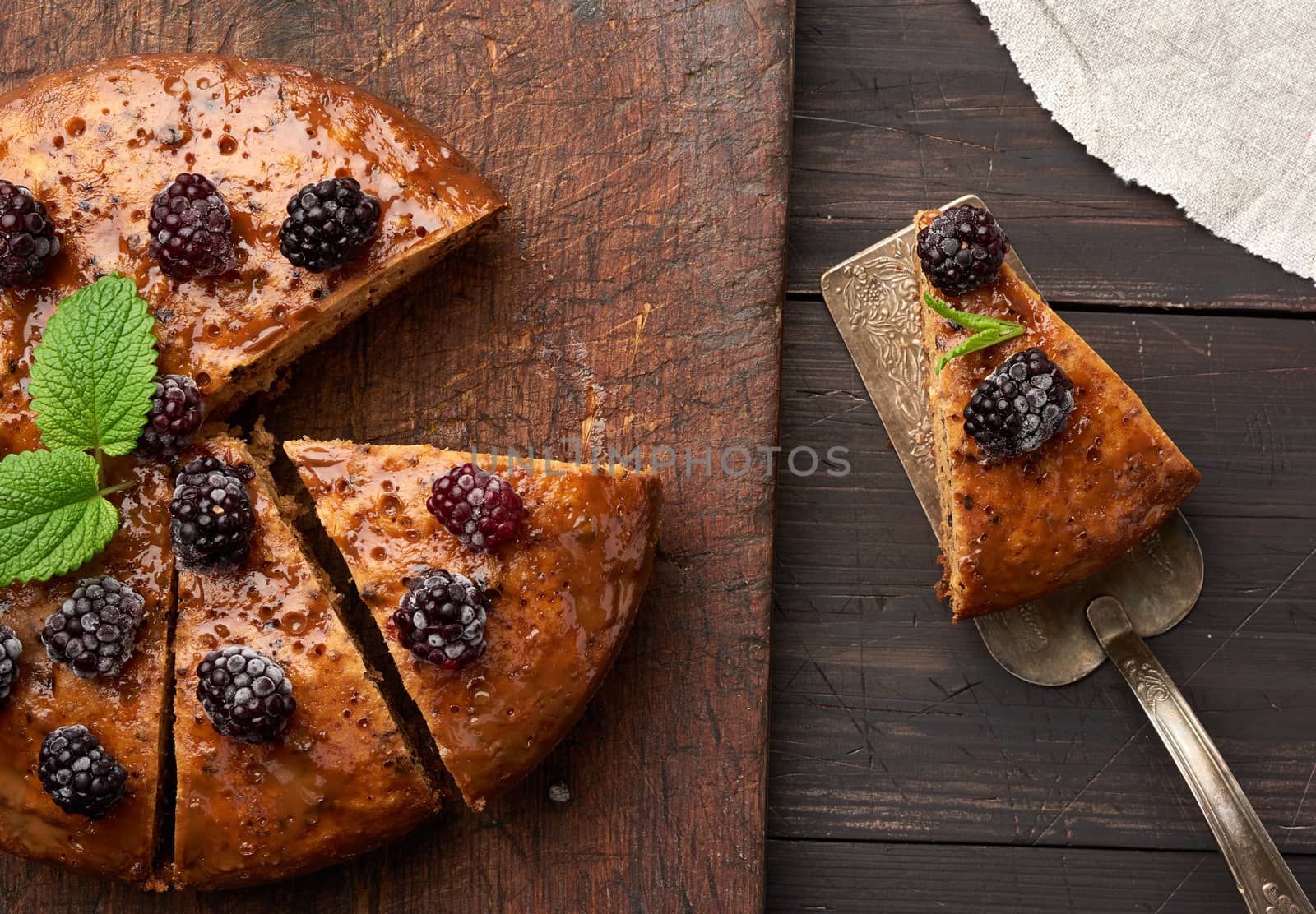 baked round biscuit cake with nuts and berries topped, wooden brown table, top view