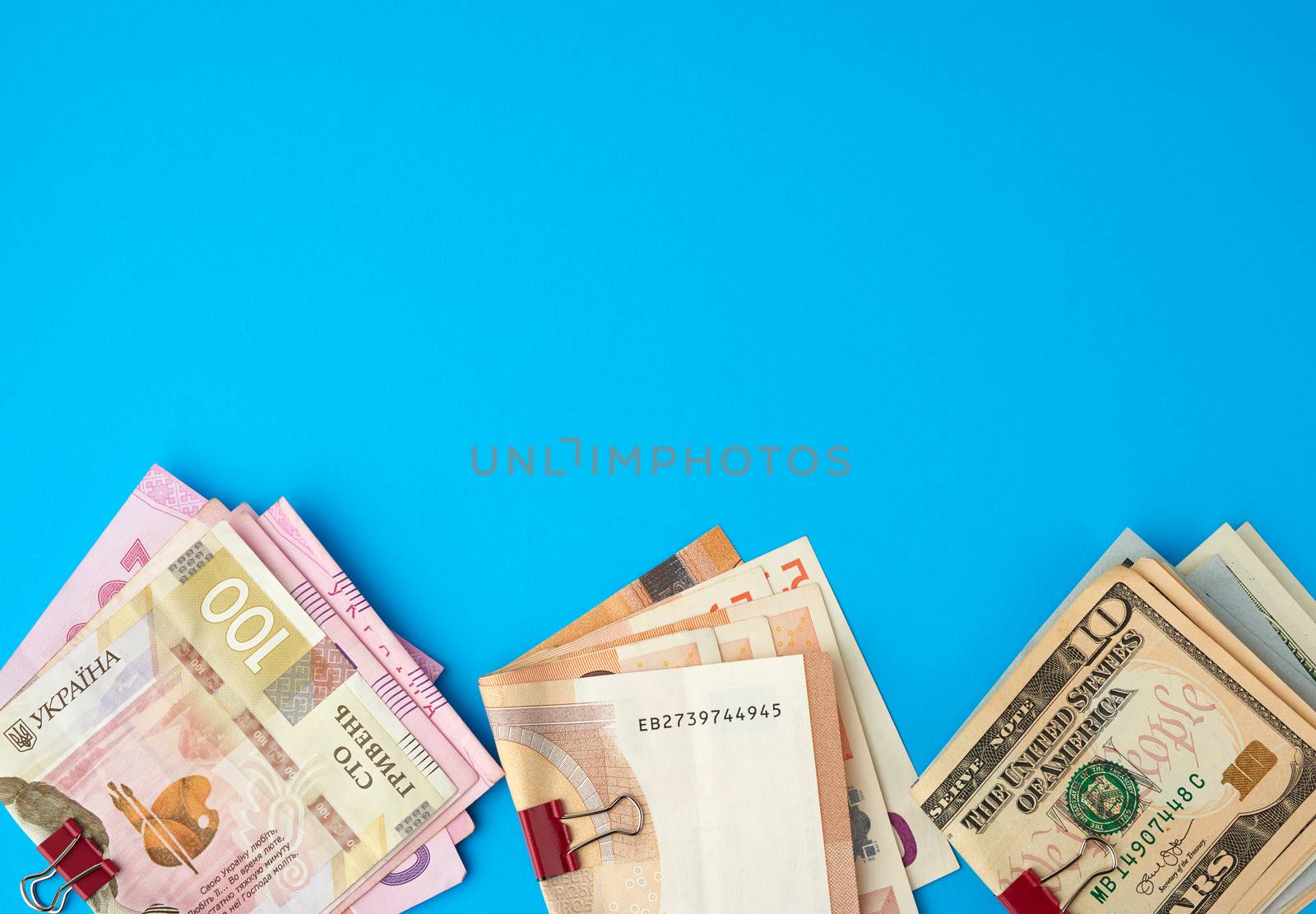 Ukrainian hryvnia, EU paper money euro and american dollars on blue background, concept of wealth, investment exchange, crisis, copy space