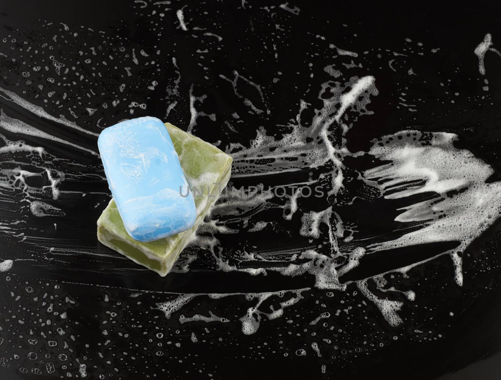 white soap foam and soap on a black background, top view, concept of cleanliness, antibacterial