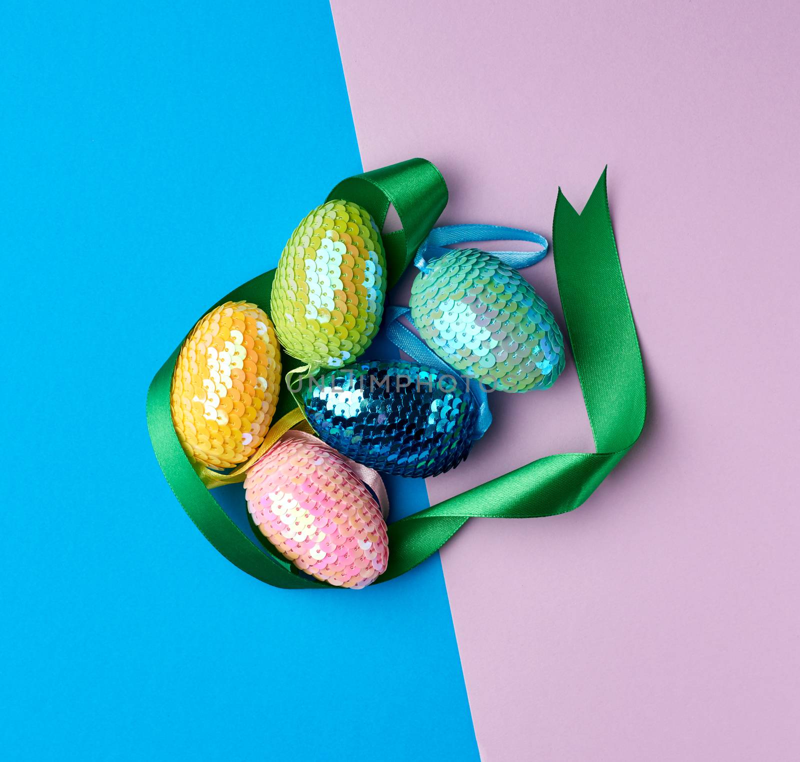 multicolored decorative Easter eggs decorated with sequins on a color background, festive green background, top view
