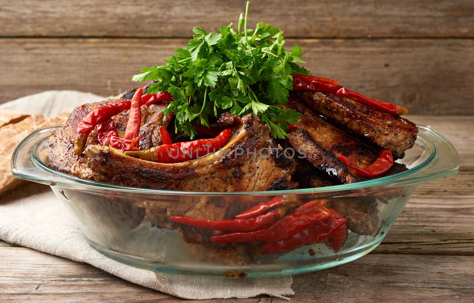 grilled pork steaks on the bone lie in a transparent glass plate on a wooden table, barbecue