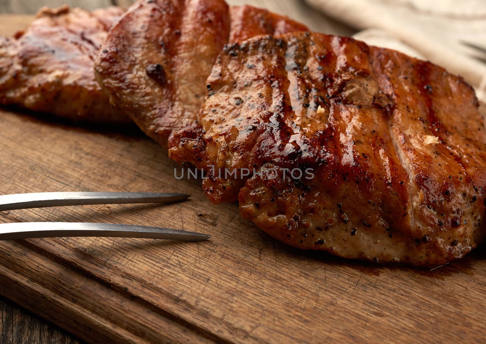 fried juicy pork steak on a wooden board, grilled meat, close up