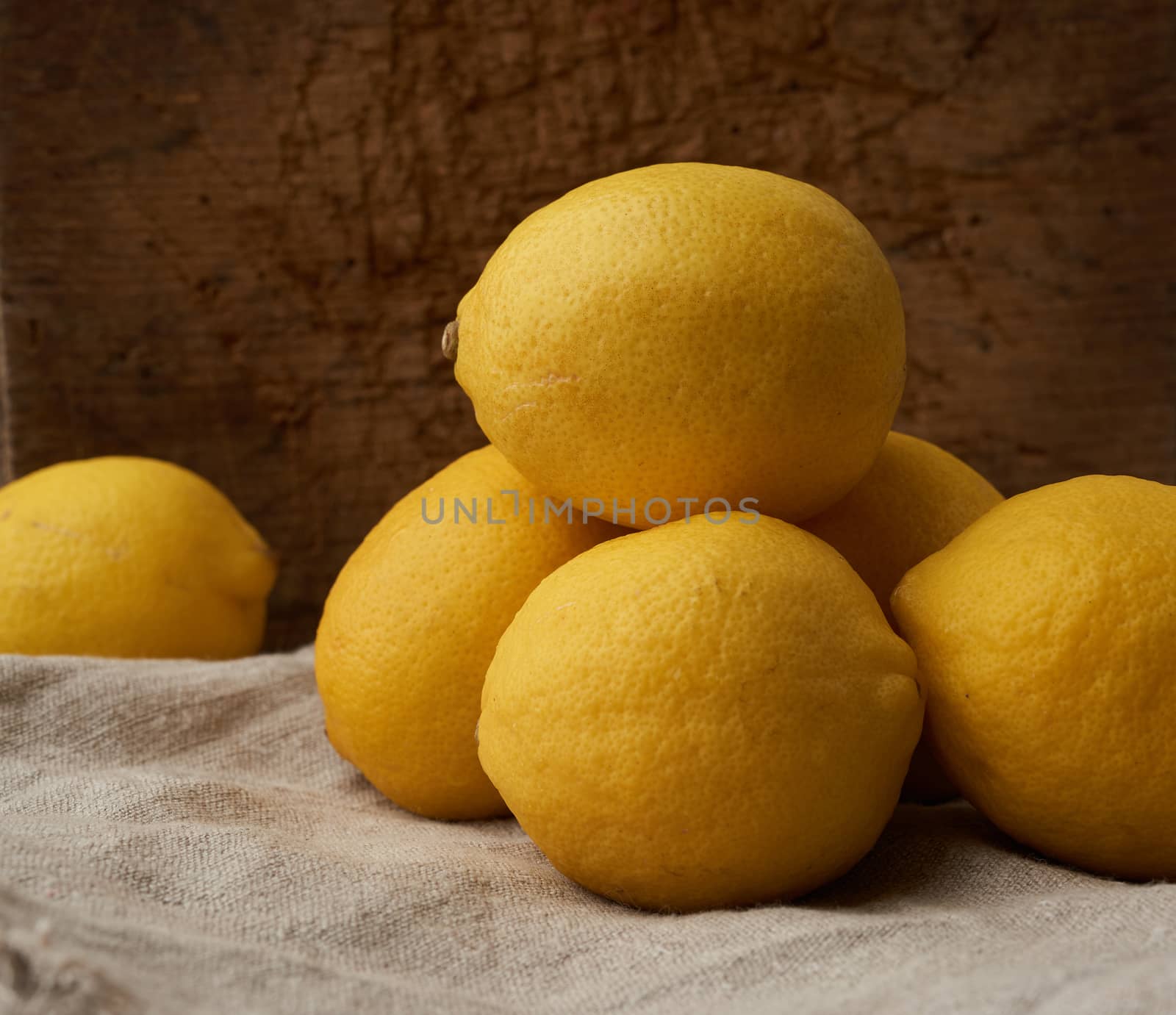 stack of yellow round lemons on a gray textile napkin, close up