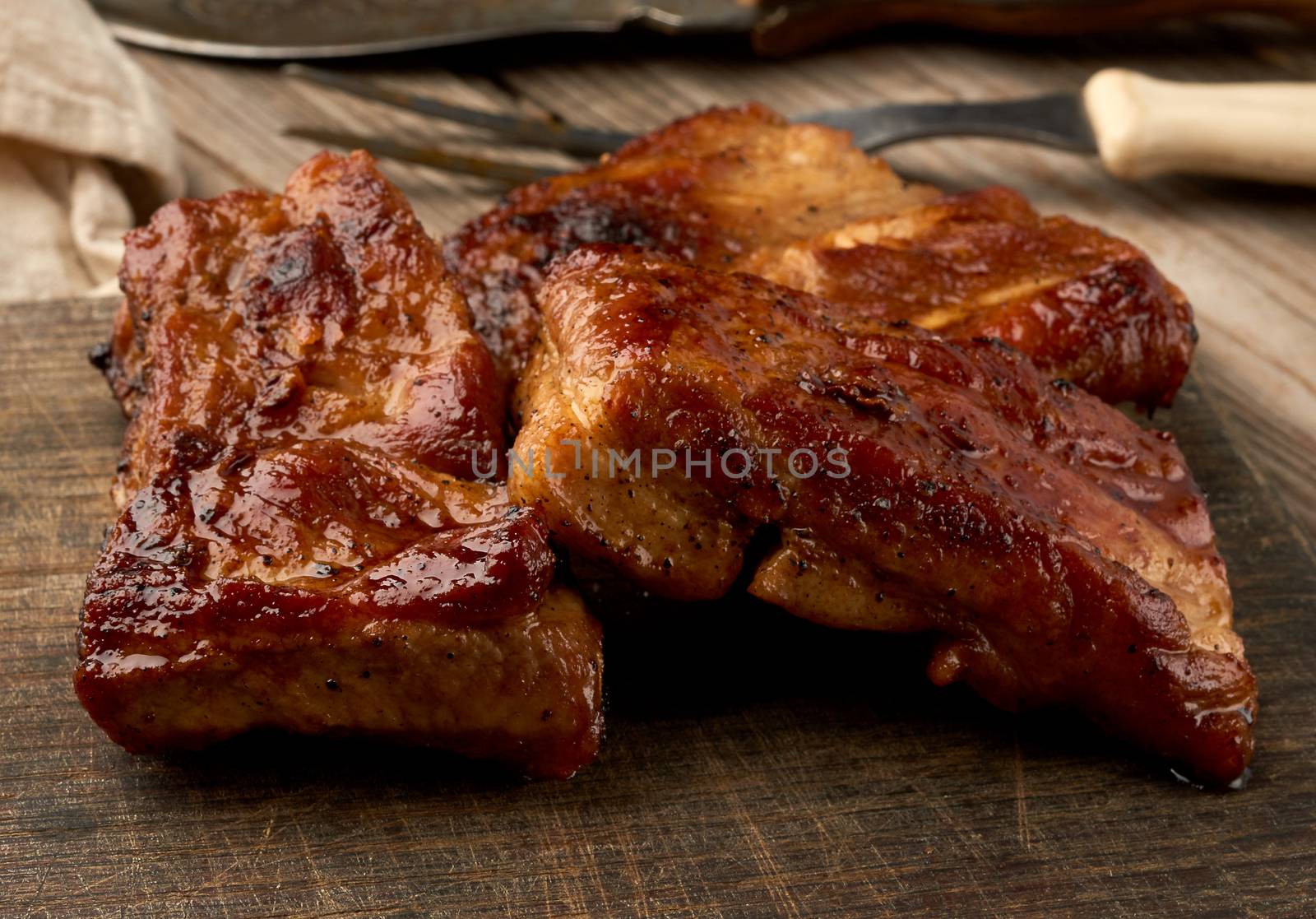 fried juicy pork meat on the bone on a wooden board, grilled meat, close up