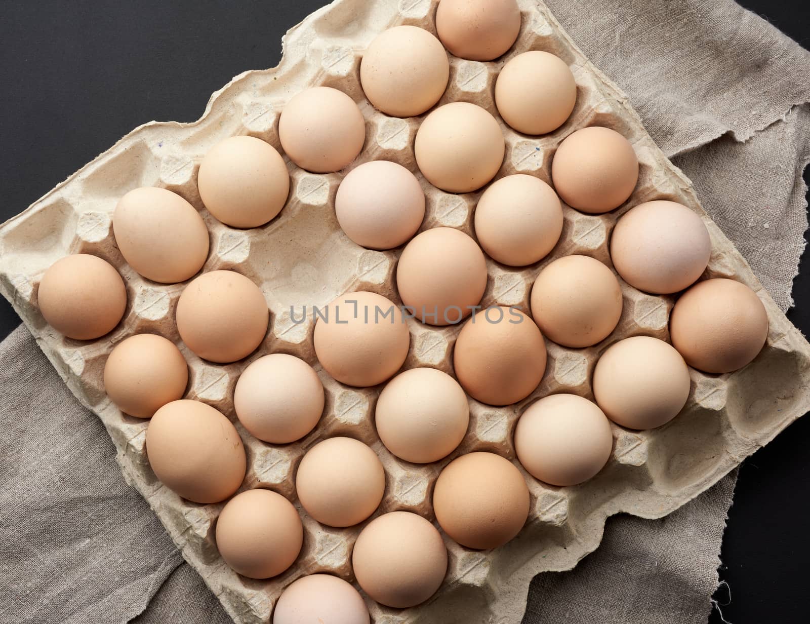 whole round raw brown homemade chicken eggs in a paper tray, top view