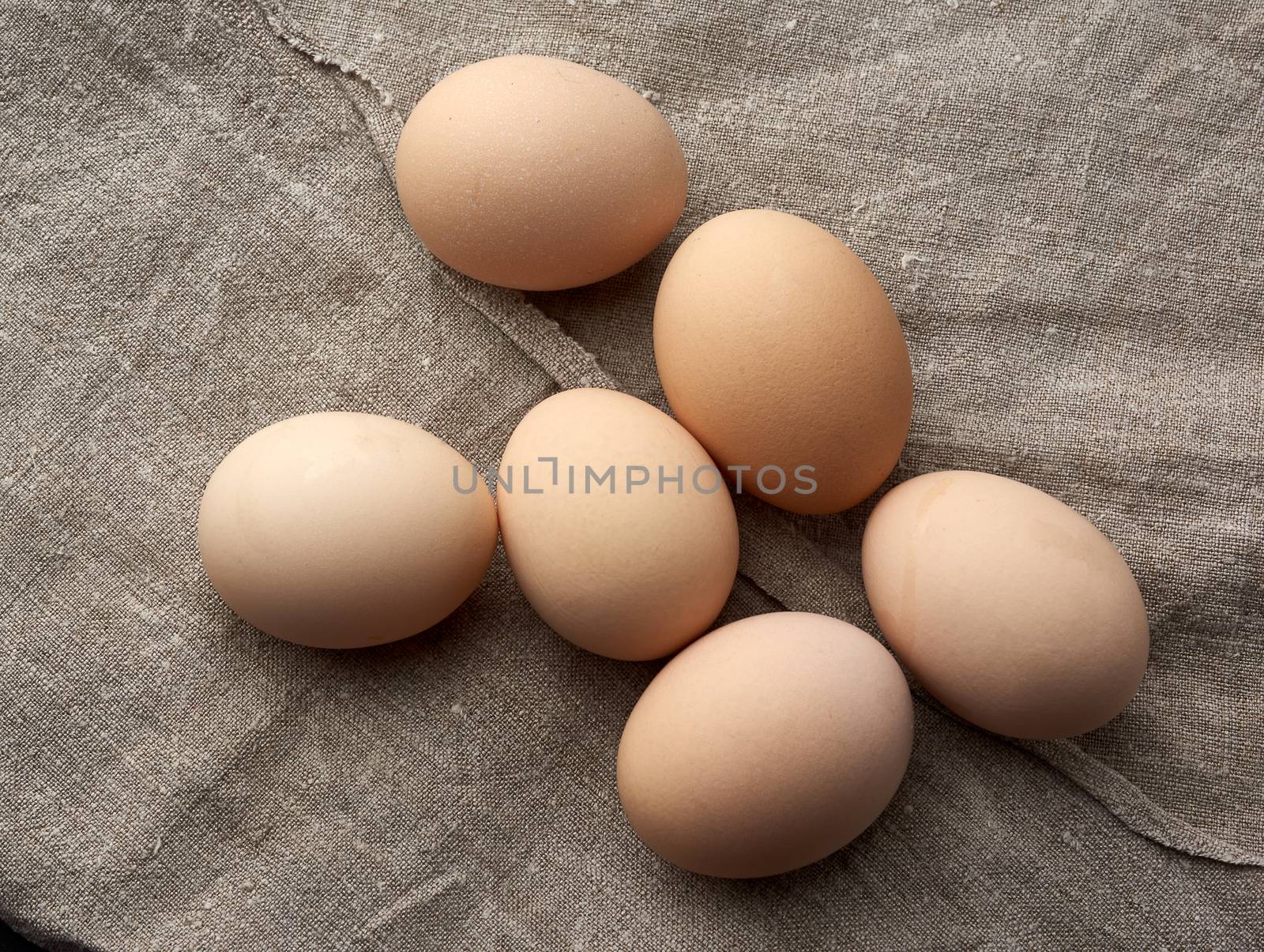 whole broken raw brown homemade chicken eggs on a gray linen napkin, top view