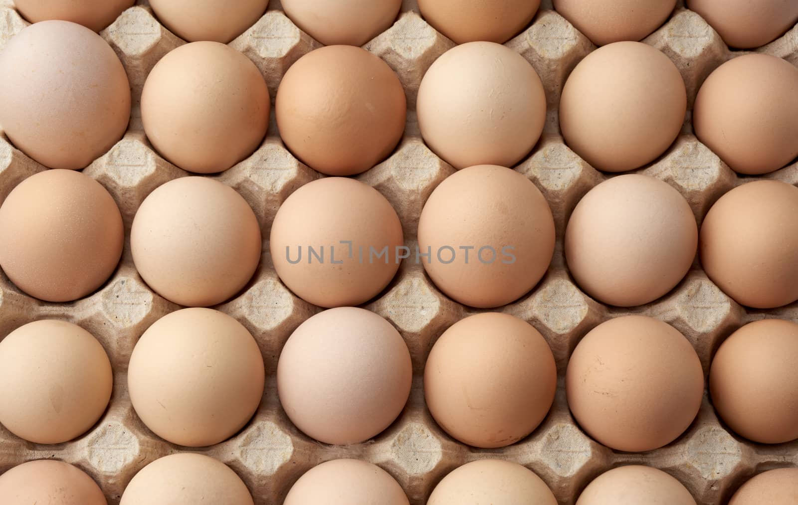 whole round raw brown homemade chicken eggs in a paper tray, selective focus, close up
