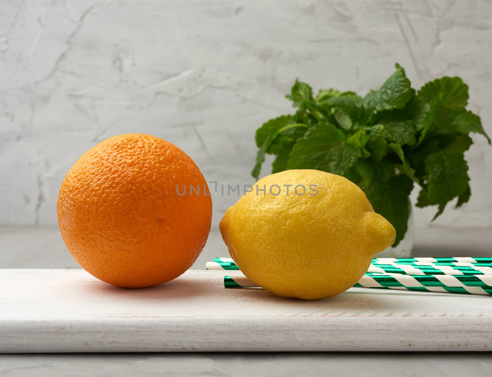 whole orange, yellow ripe lemon and a bunch of mint on a wooden board, ingredients for lemonade