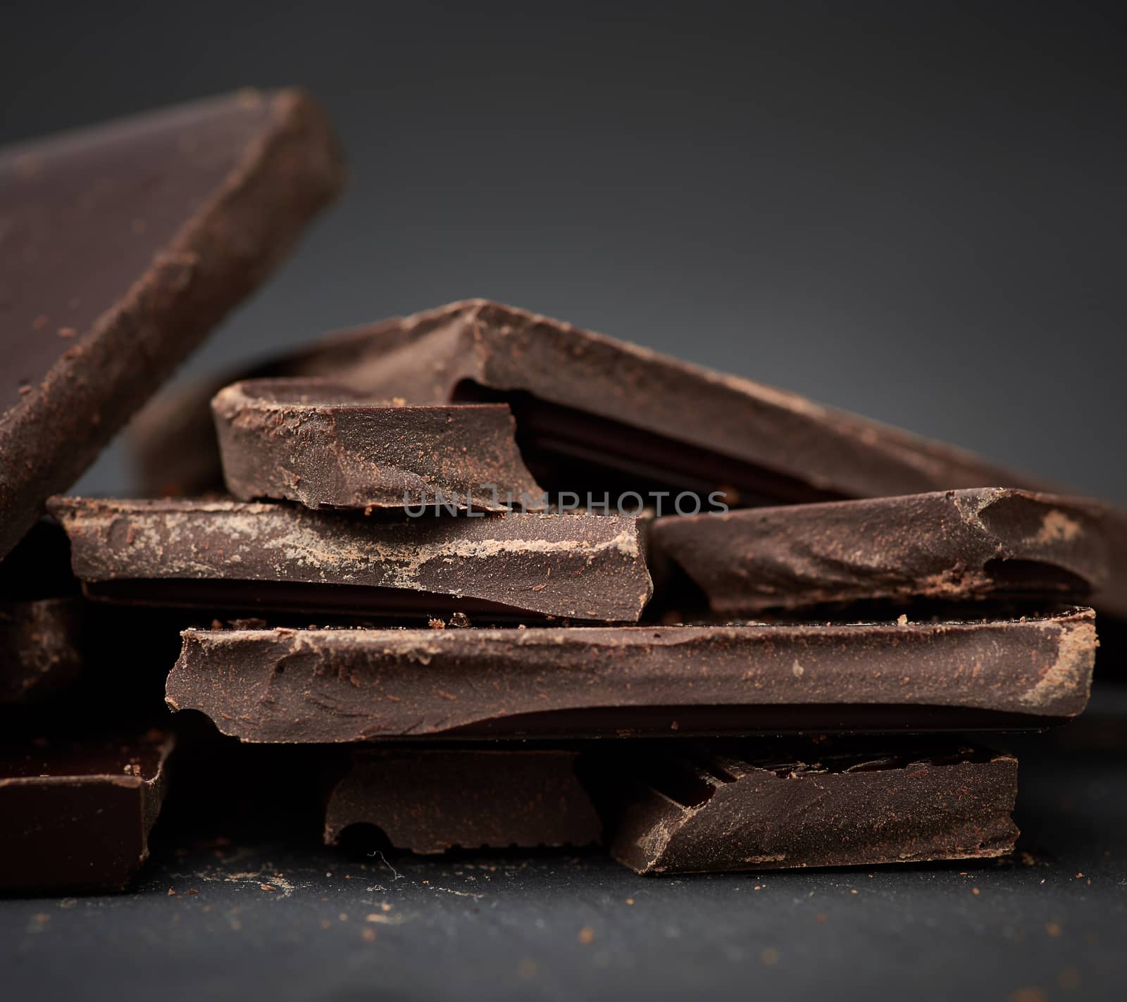 pieces of black chocolate on a black background, sweet dessert, close up